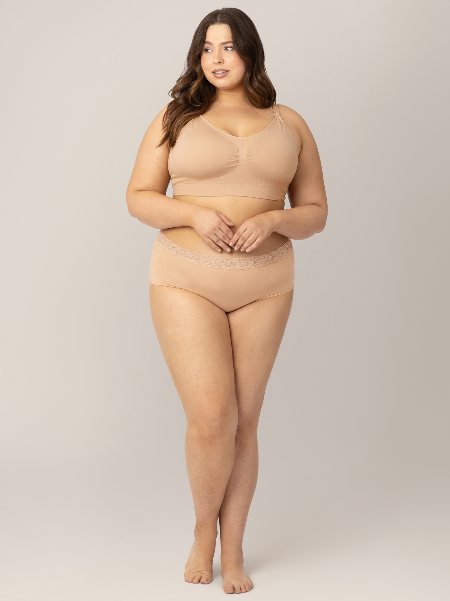 Model wearing the  High-Waisted Postpartum Underwear in Assorted Neutrals  with her hands near her stomach. @model_info:Bailey is wearing a 1X.
