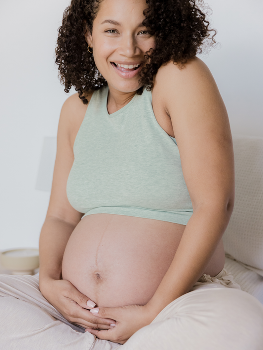 Pregnant model sitting and wearing the Sublime® Bamboo Maternity & Nursing Longline Bra in dusty blue green heather. @model_info:Alysha is wearing a Large.