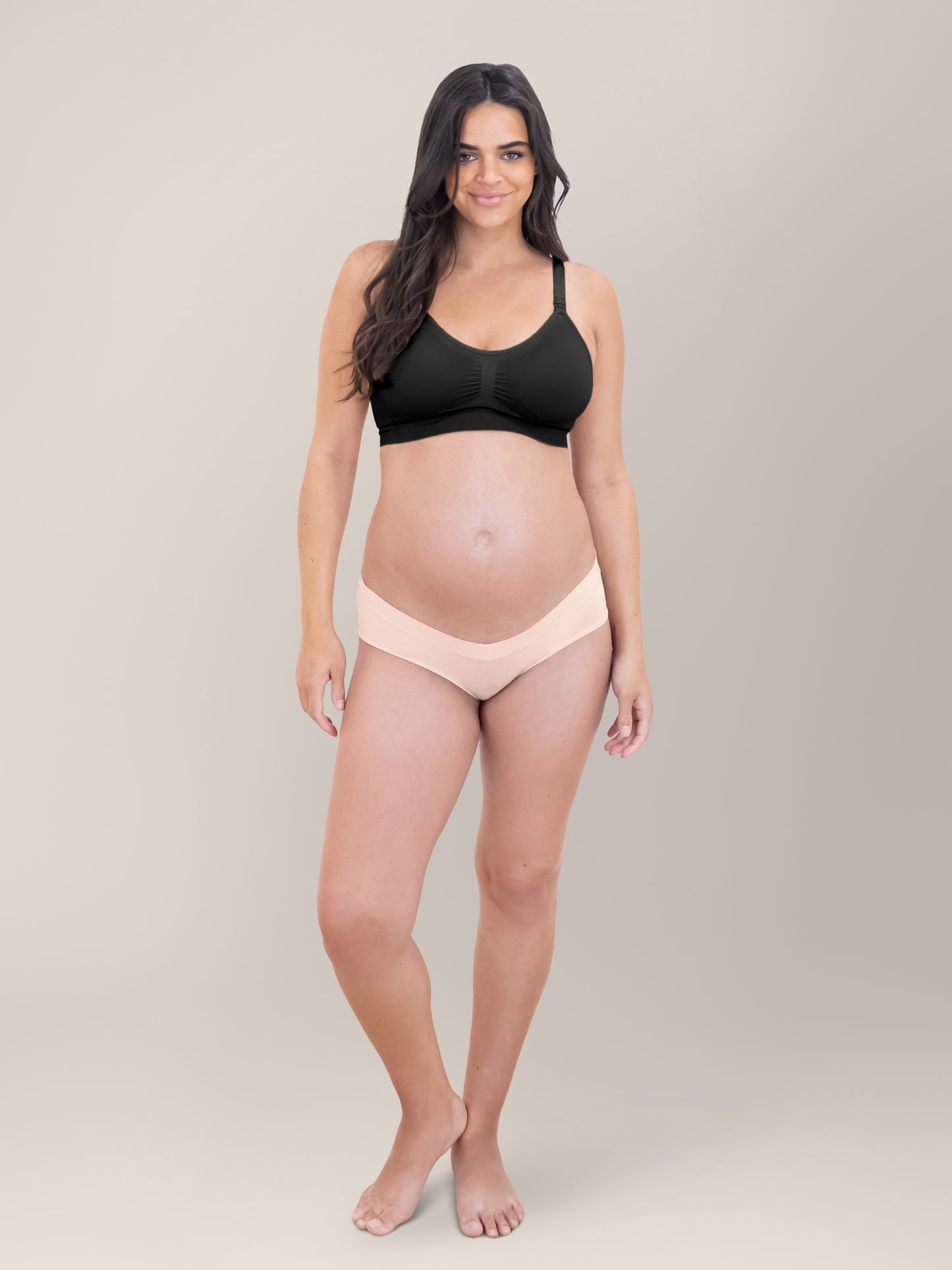 Model standing in front of a grey background with her hands at her sides wearing the Grow with Me™ Maternity & Postpartum Hipster in Soft Pink.