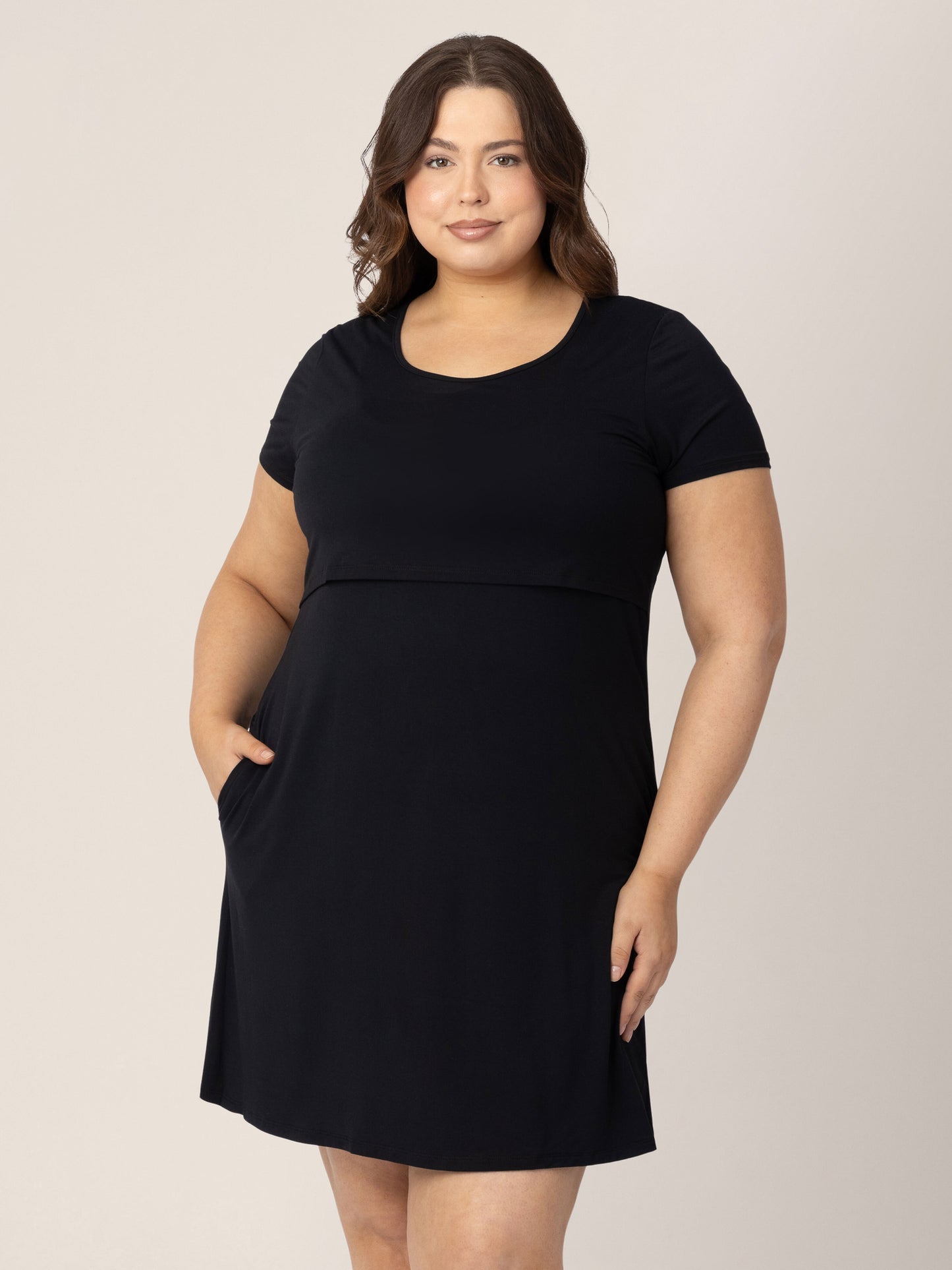 Model wearing the Eleanora Bamboo Maternity & Nursing Dress in Black with her hand in her pocket. @model_info:Bailey is 5'10" and wearing an X-Large.