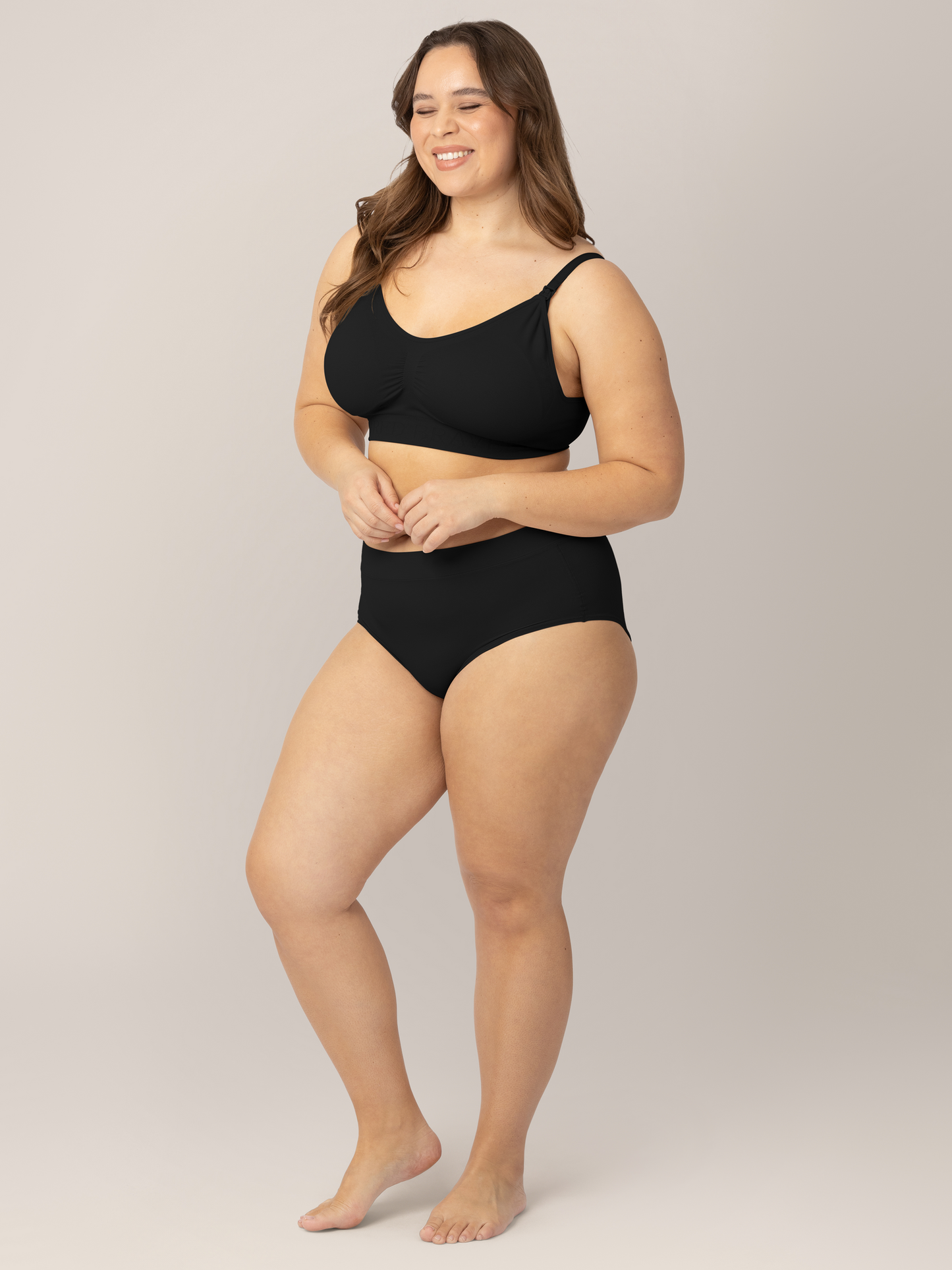Model wearing the Grow with Me™ Maternity & Postpartum Brief in Black with her hands near her stomach.