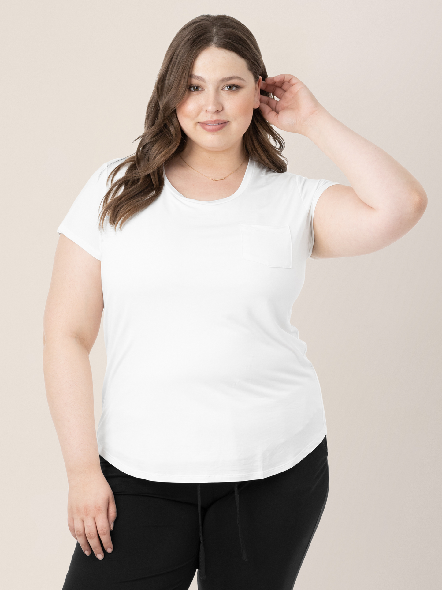 Model wearing the Everyday Maternity & Nursing T-shirt in White tucking her hair behind her ear.@model_info:Bailey is wearing an X-Large.
