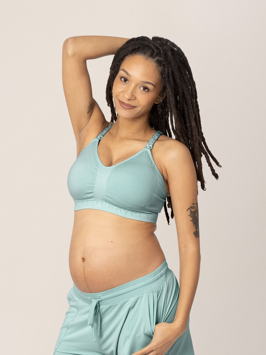 Model with her hand in her hair wearing the Sublime® Hands-Free Pumping & Nursing Sports Bra in Dusty Blue Green@model_info:Chrissy is wearing a Small Busty.