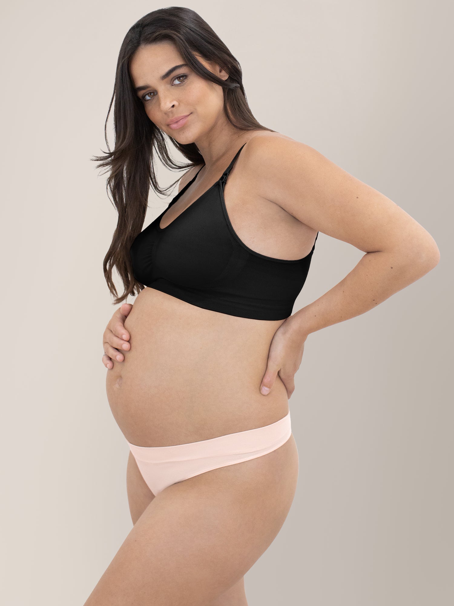 Side view of a pregnant model wearing the Bamboo Maternity & Postpartum Thong in Soft Pink 