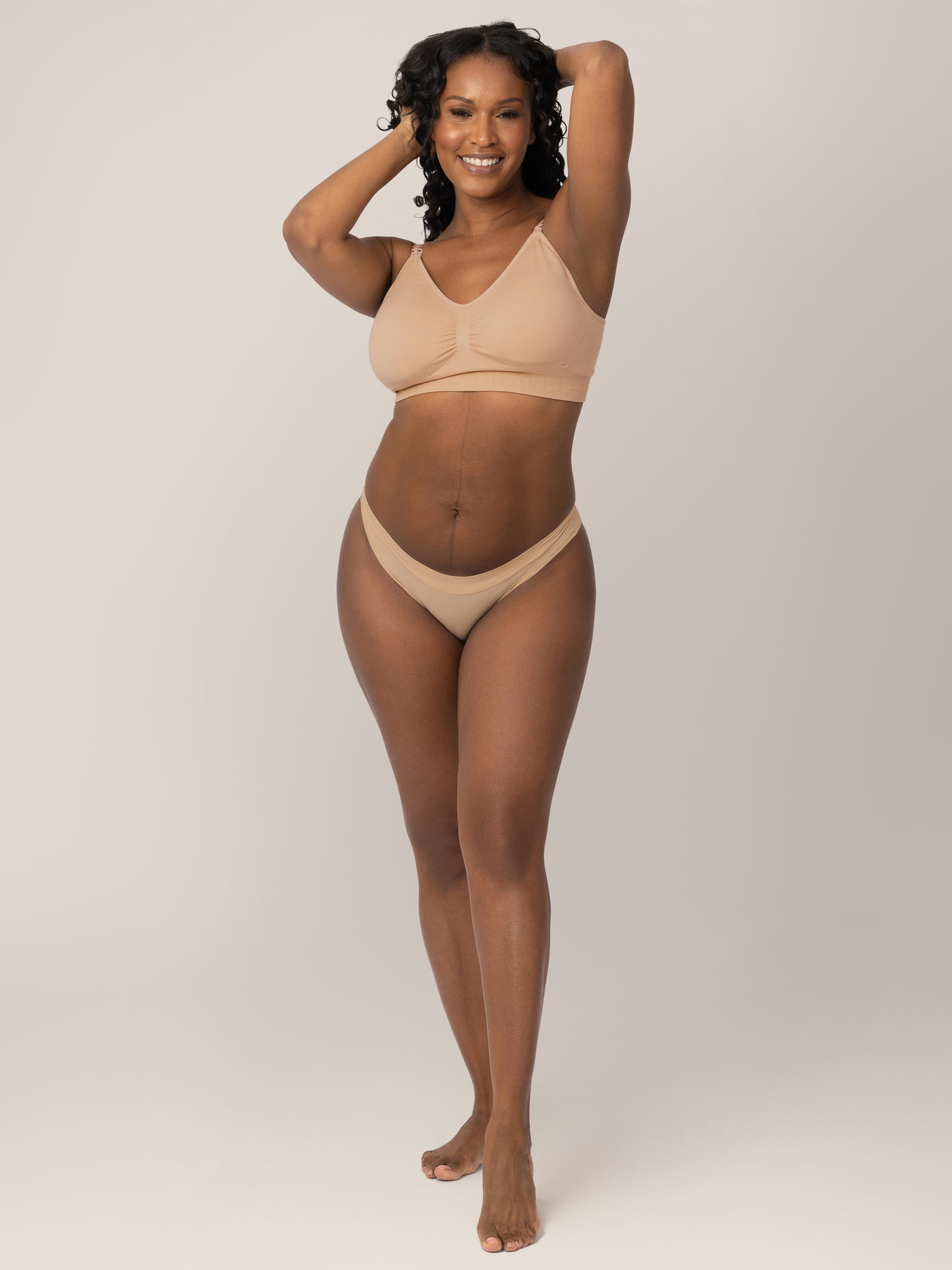 Model wearing the Grow with Me™ Maternity & Postpartum Thong in Beige with her hands in her hair.