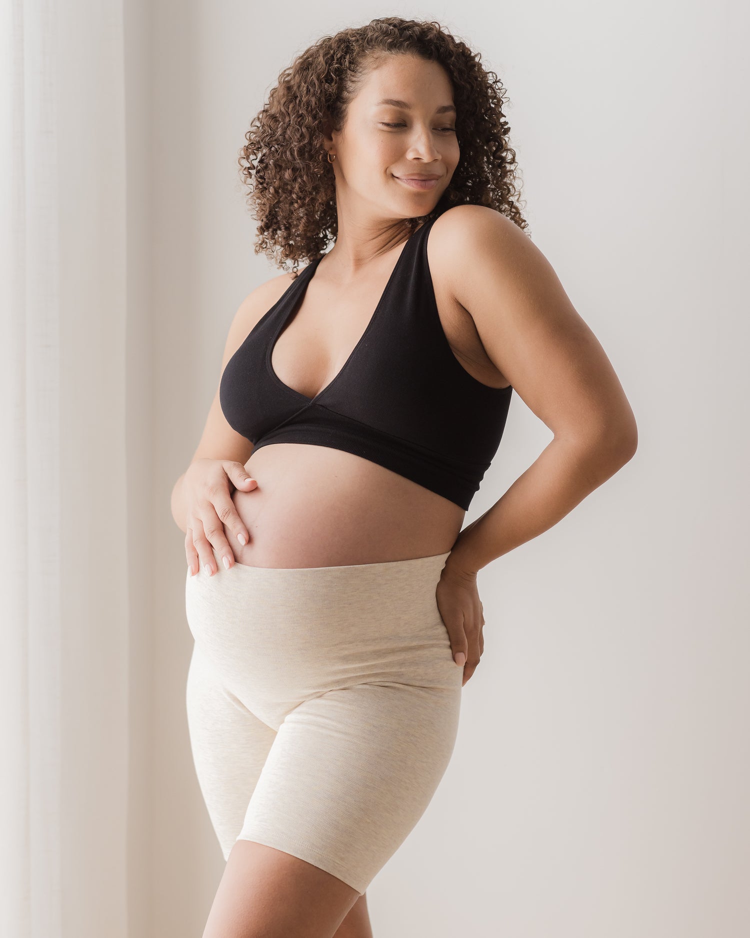 Pregnant model wearing the Sublime® Bamboo Maternity & Postpartum Bike Short in oatmeal heather, paired with the Sublime® Bamboo Maternity & Nursing Plunge Bra in black@model_info:Alysha is 5'6" and wearing a Large.