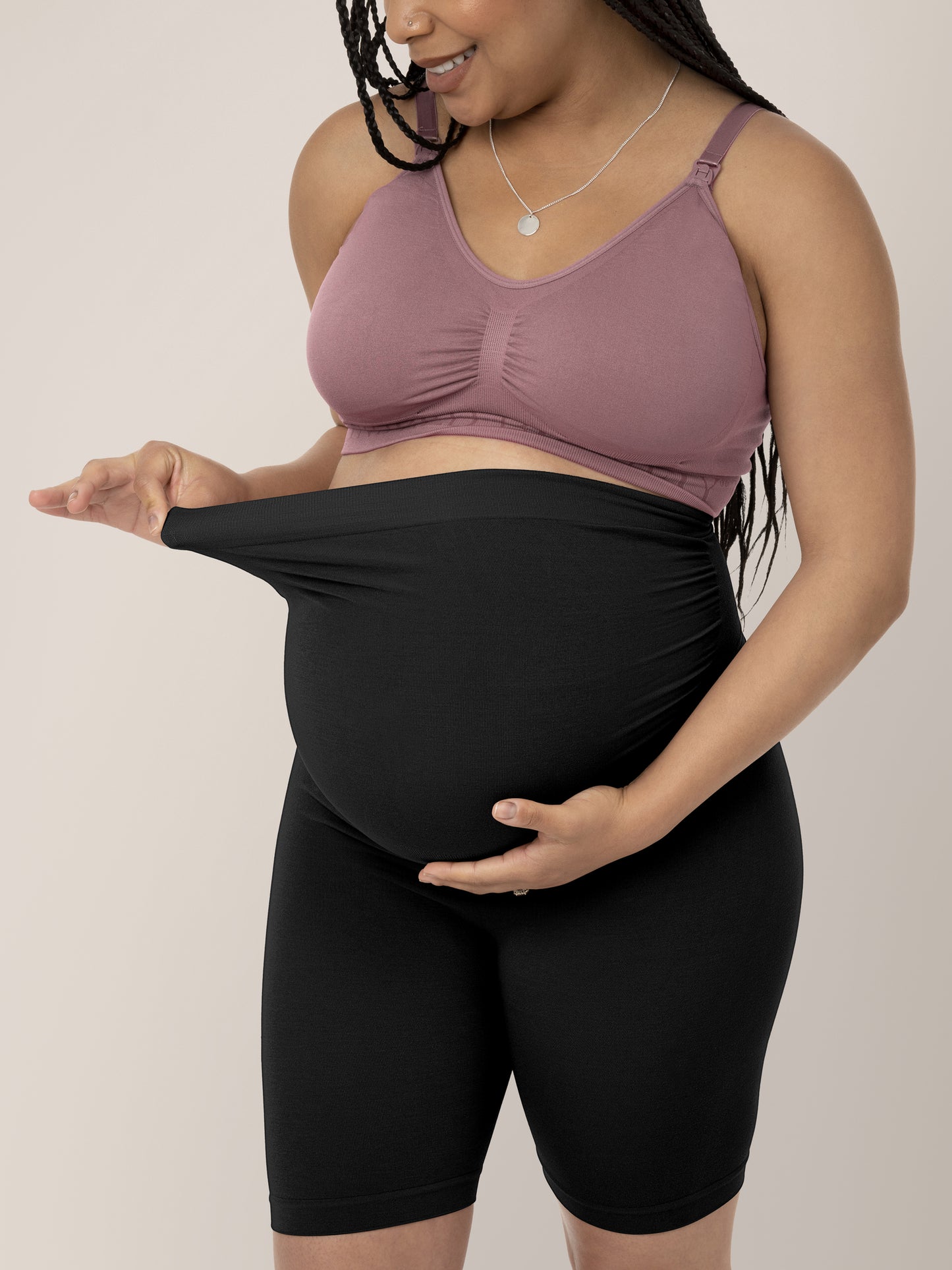 Model holding onto the waistband of the Seamless Bamboo Maternity Thigh Savers in Black @model_info:Ruby is wearing a Medium.
