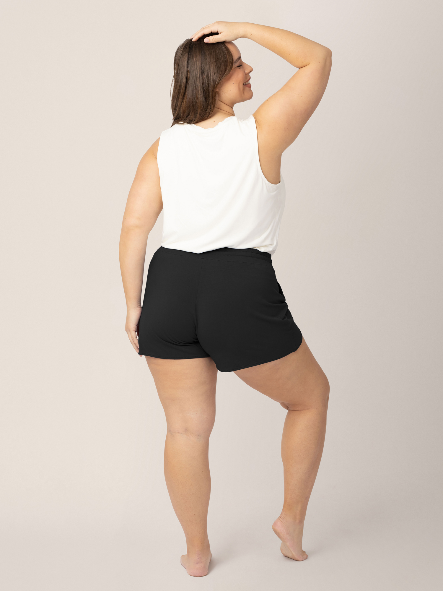 Back view of a model wearing the Bamboo Maternity & Postpartum Lounge Short in Black with a white tank top.