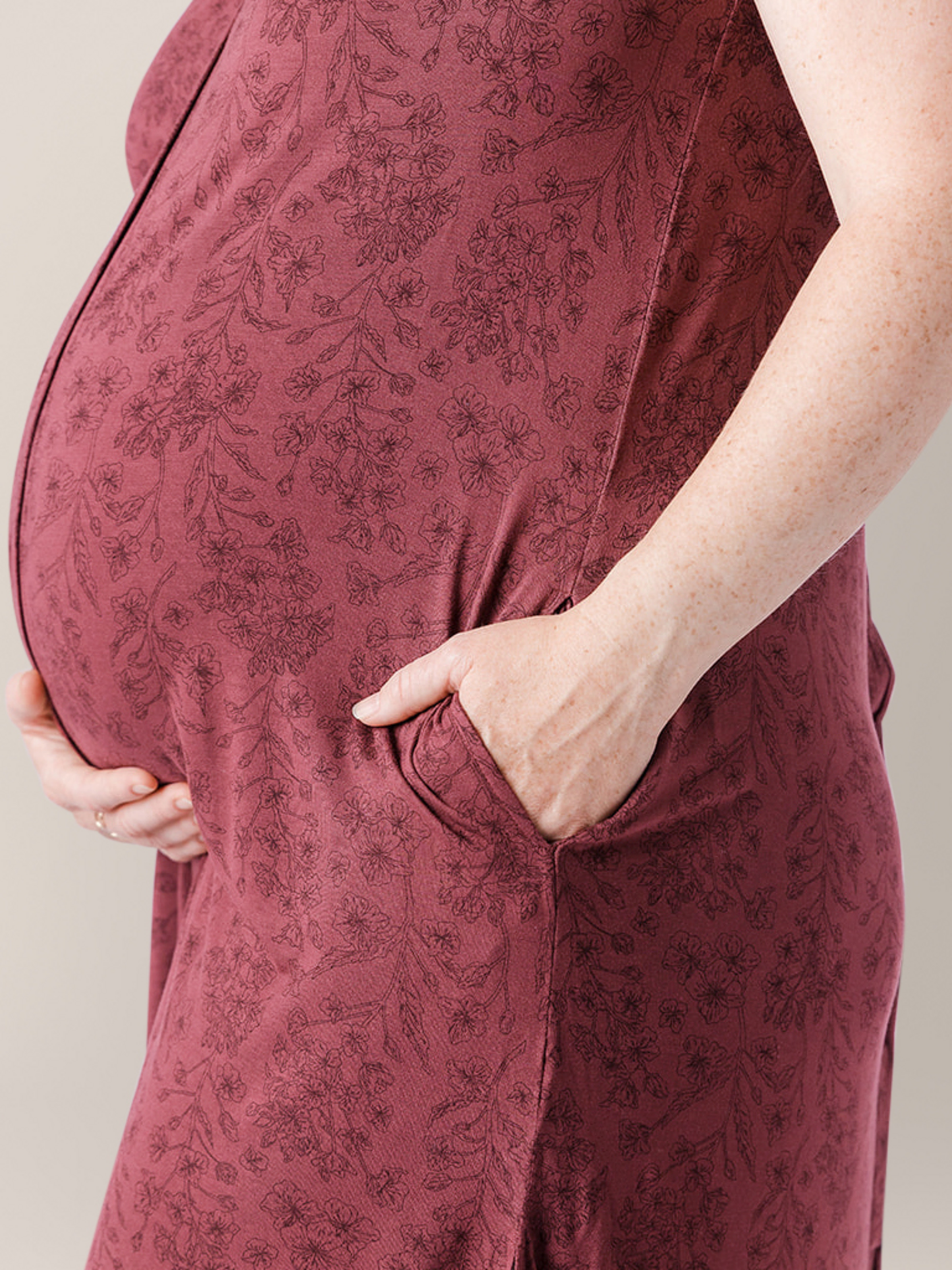 Pregnant model wearing the Ruffle Strap Labor & Delivery Gown in Spice Floral with her hand in the pocket.