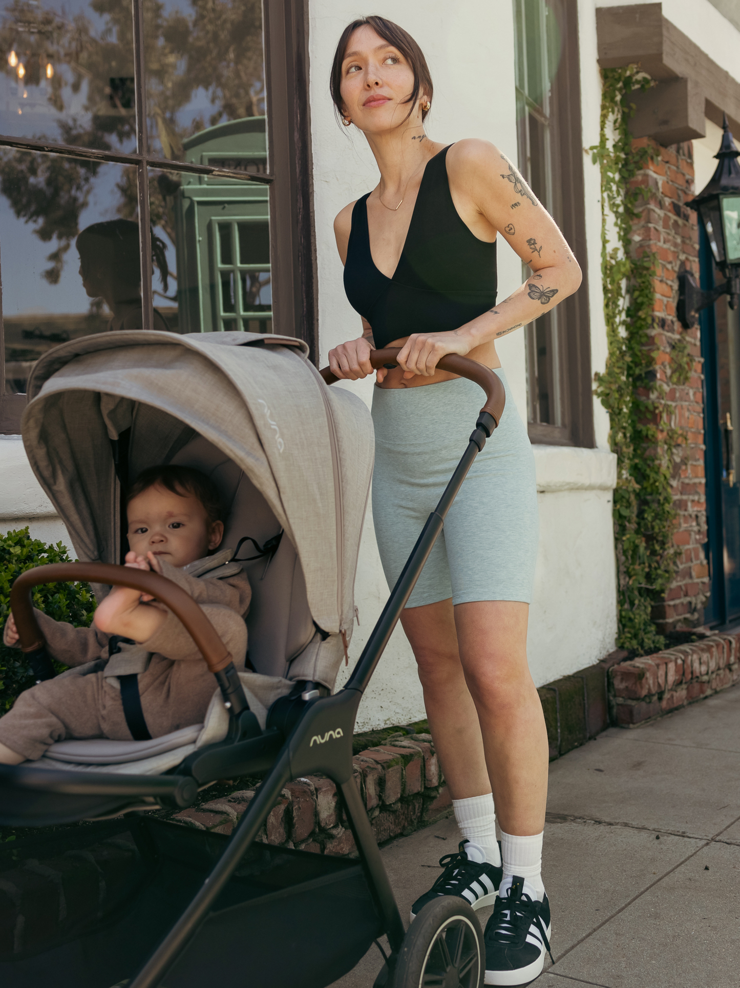 Lifestyle image of model pushing her baby in a stroller. The model is wearing the Sublime Bamboo Nursing & Maternity Plunge Bra with the Sublime Bamboo Bike Shorts.