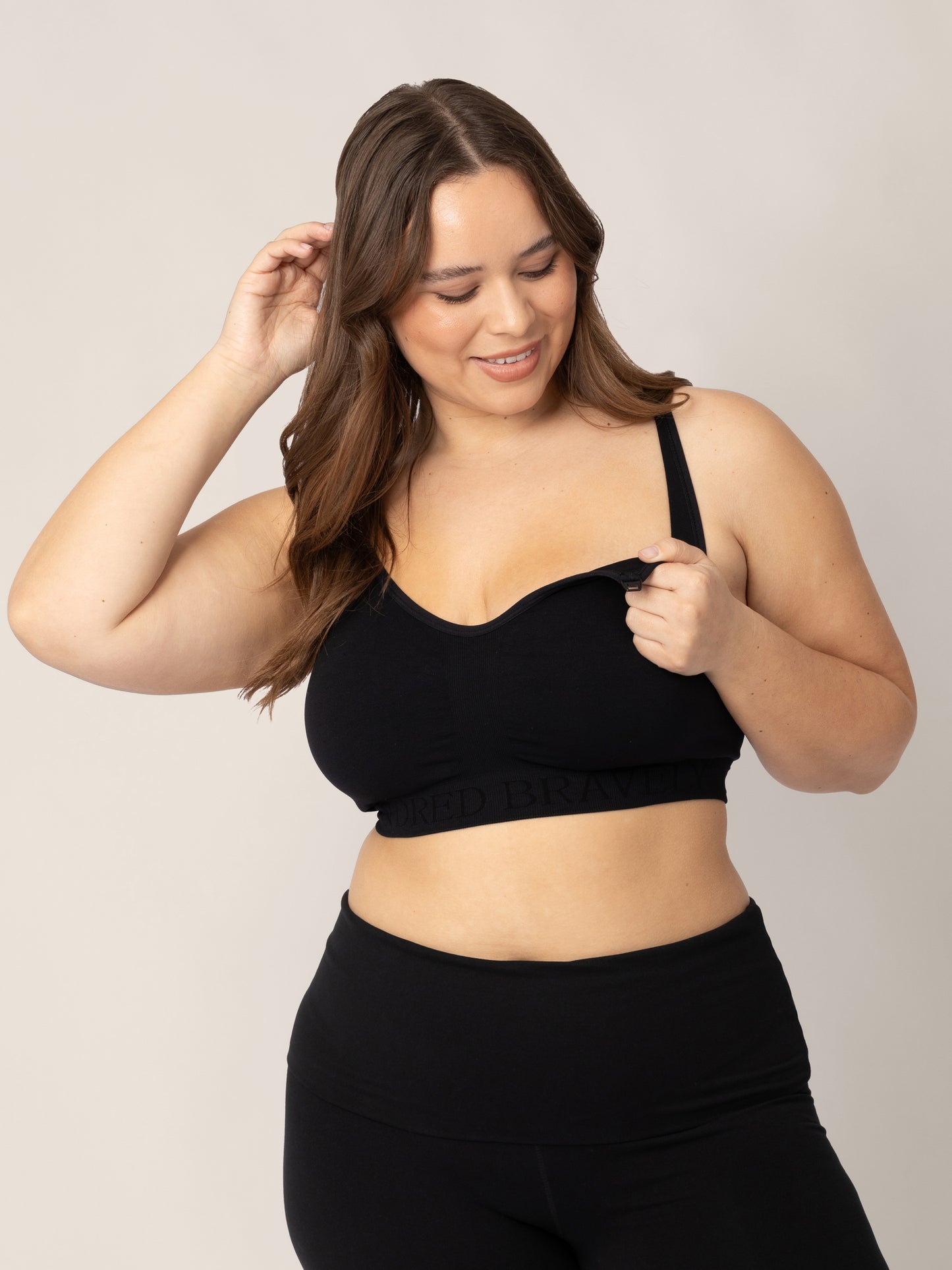 Model wearing the Sublime® Nursing Sports Bra in black showing off the easy clip nursing access.@model_info:Venezia is wearing a Large Busty. 