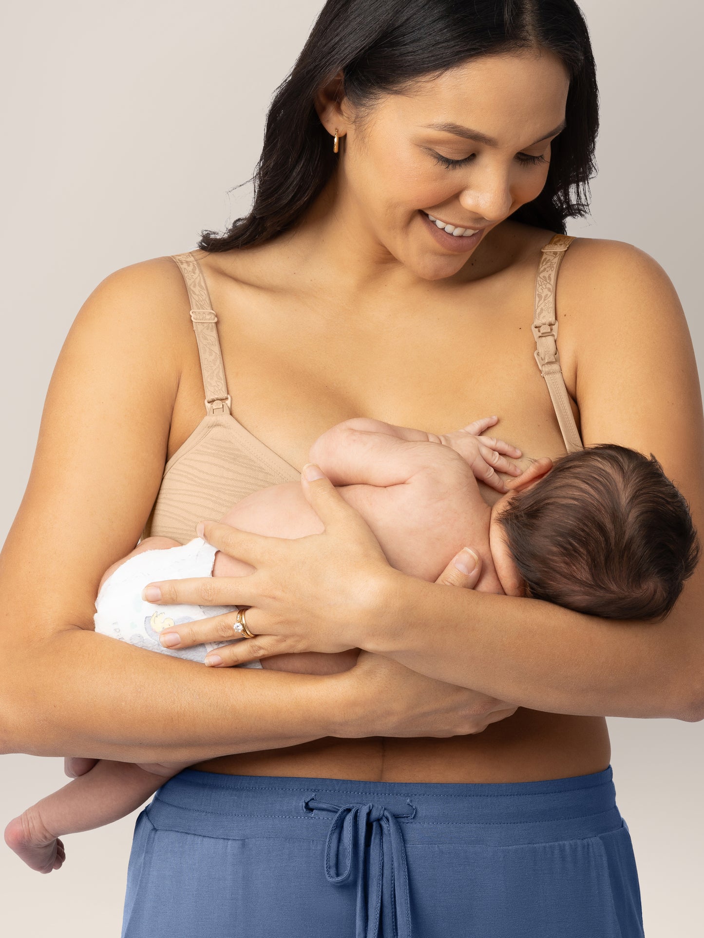Model breastfeeding her baby while wearing the Sublime® Hands-Free Pumping & Nursing Bra in Beige