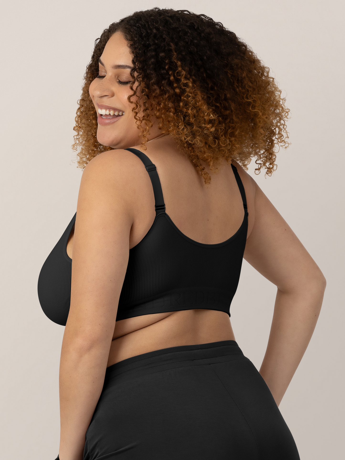 Back of a busty model wearing the Sublime® Adjustable Crossover Nursing & Lounge Bra in Black.