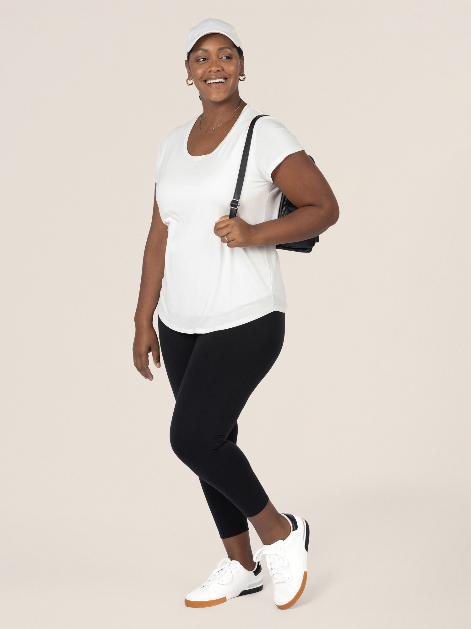 Model wearing the Everyday Maternity & Nursing T-shirt in White in sports shoes and a backpack.