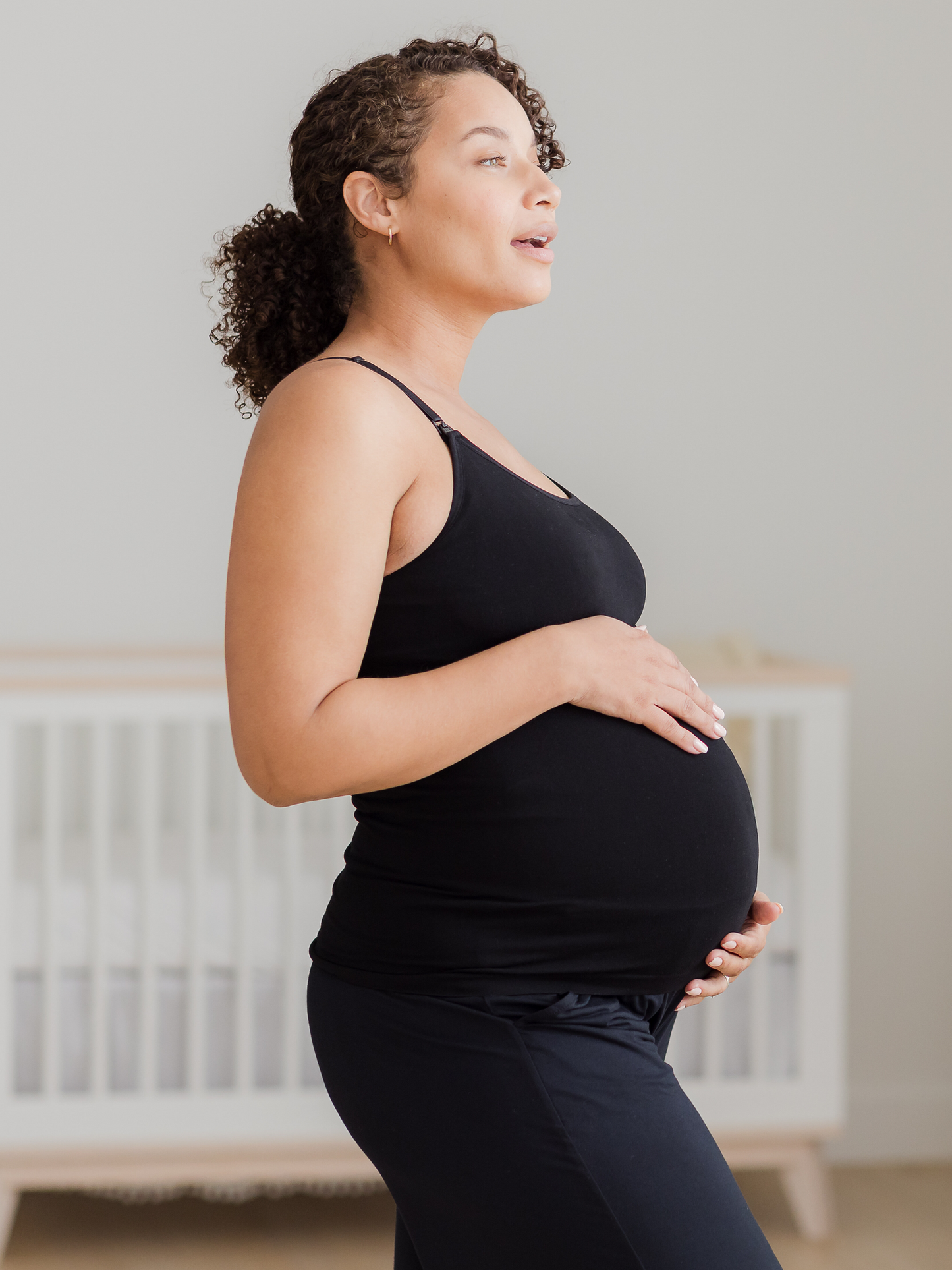 Side view of pregnant model wearing the Sublime® Bamboo Maternity & Nursing Camisole in black. @model_info:Alysha is wearing a Large.