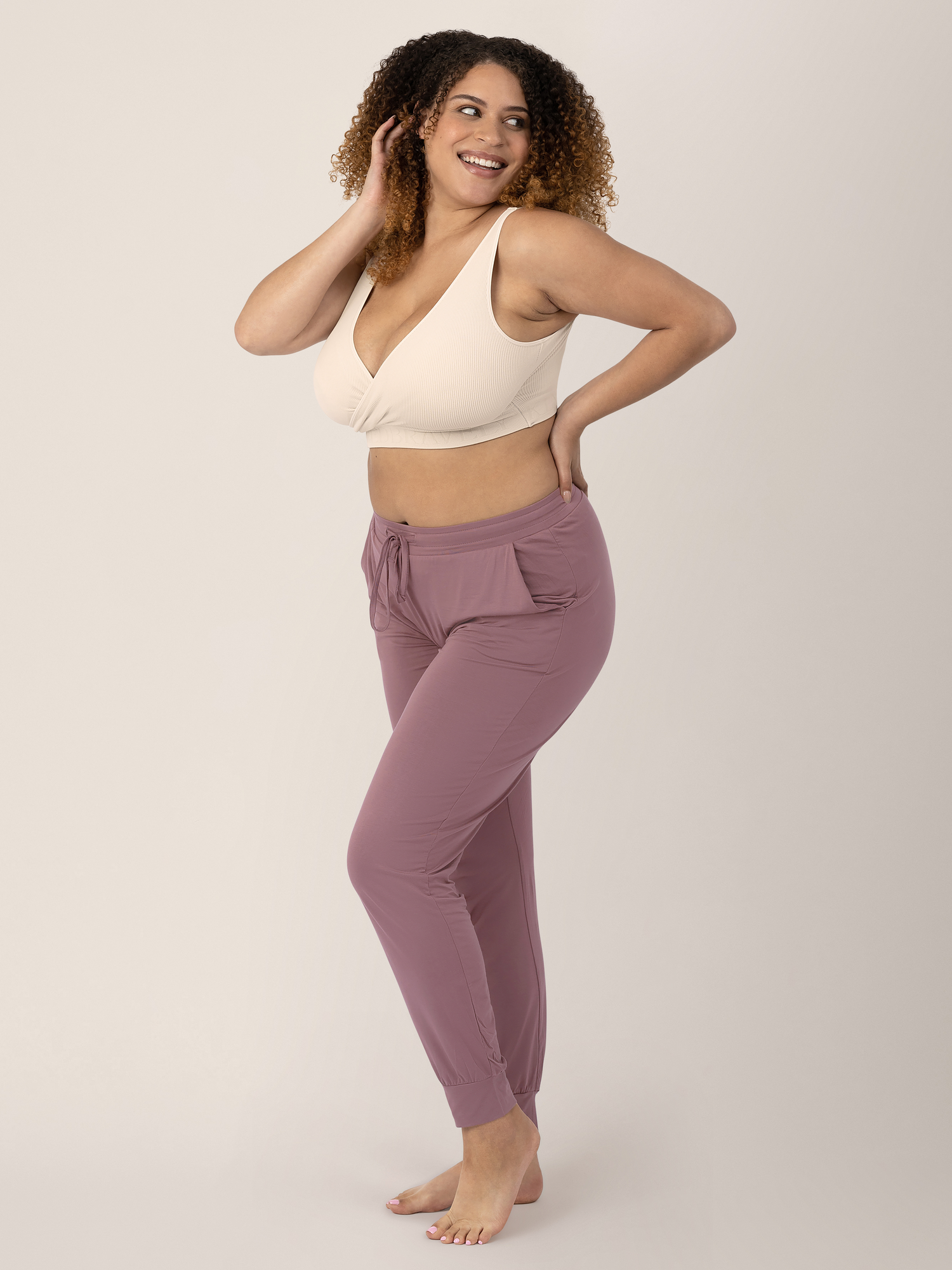 Model wearing the Sublime® Adjustable Crossover Nursing & Lounge Bra in Stone with her hand on her hip and in her hair.