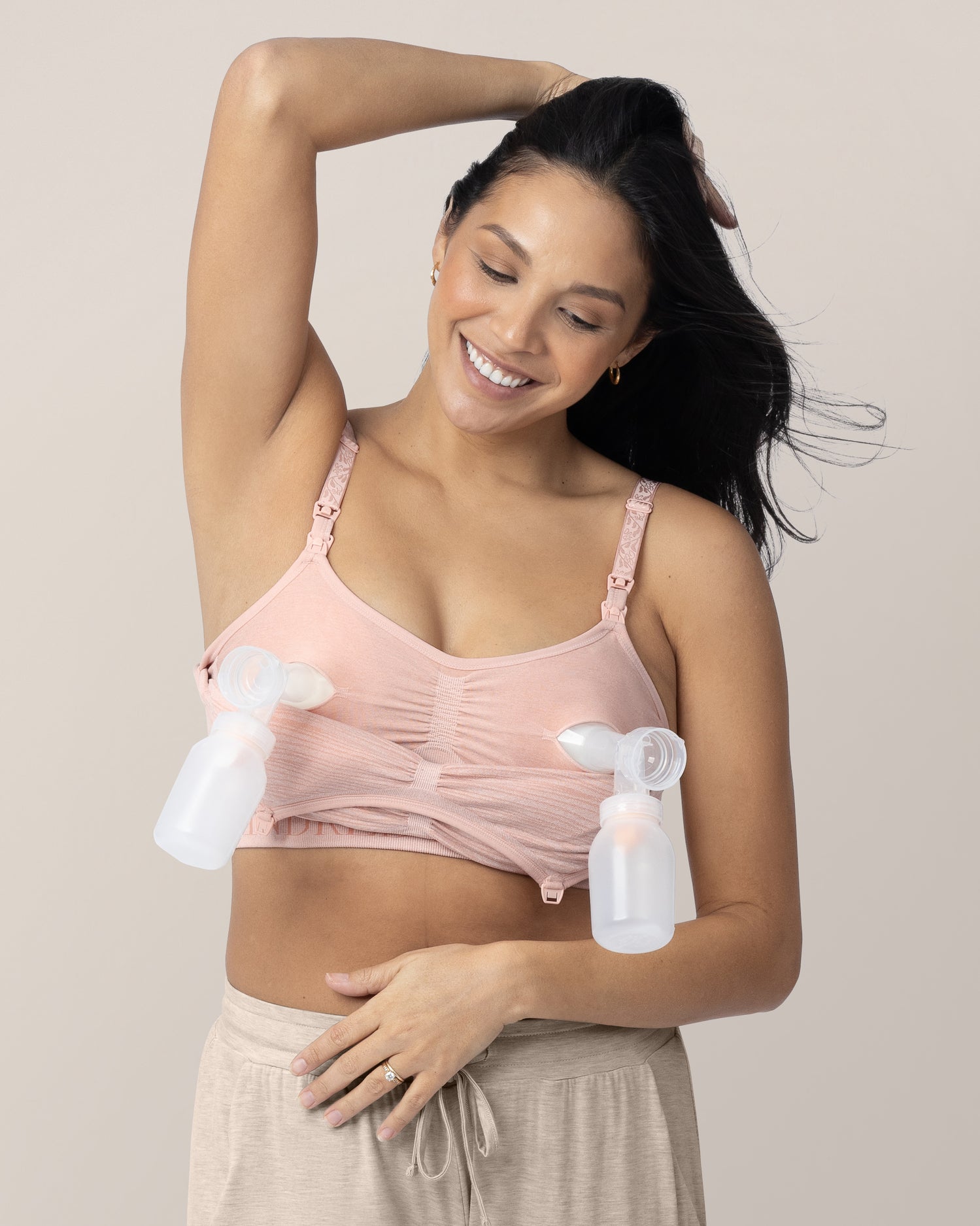 Model connected to two bottles while wearing the Sublime® Hands-Free Pumping & Nursing Bra in Pink Heather @model_info:Julana is wearing a Small.