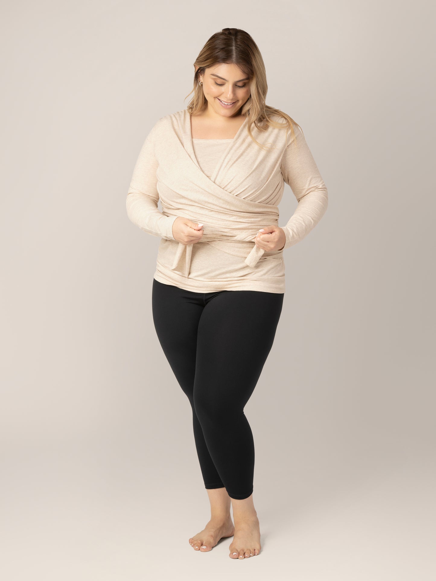 Model wearing the Organic Cotton Skin to Skin Long Sleeve Wrap Top in Oatmeal Heather, tying the straps that have been wrapped around her torso.