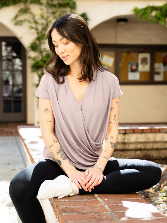 Front view of model sitting outside wearing the Bamboo Draped Nursing Top in lilac stone @model_info:Lyn is wearing a Small.