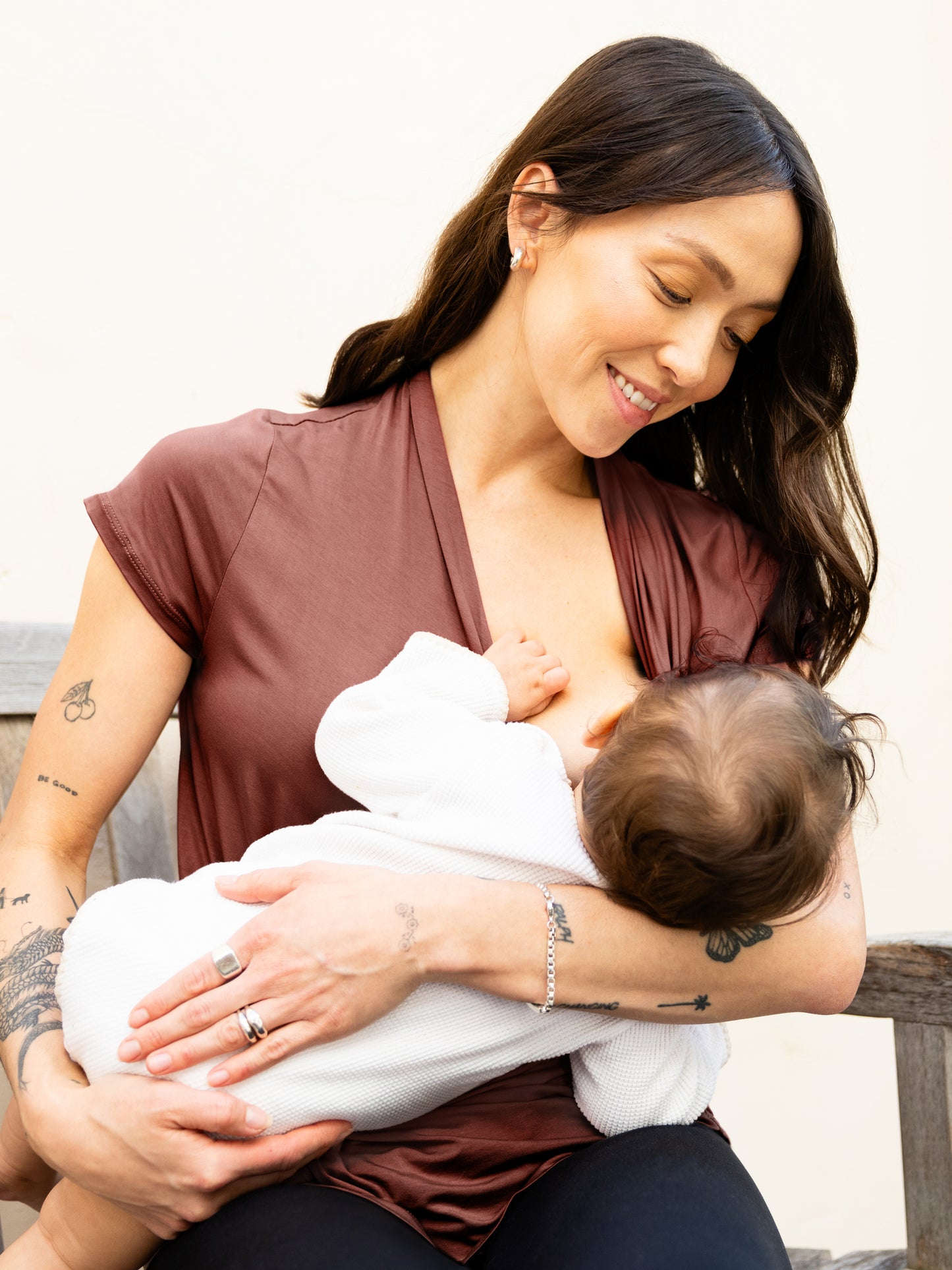 Model sitting and nursing baby, wearing the Bamboo Draped Nursing Top in redwood.