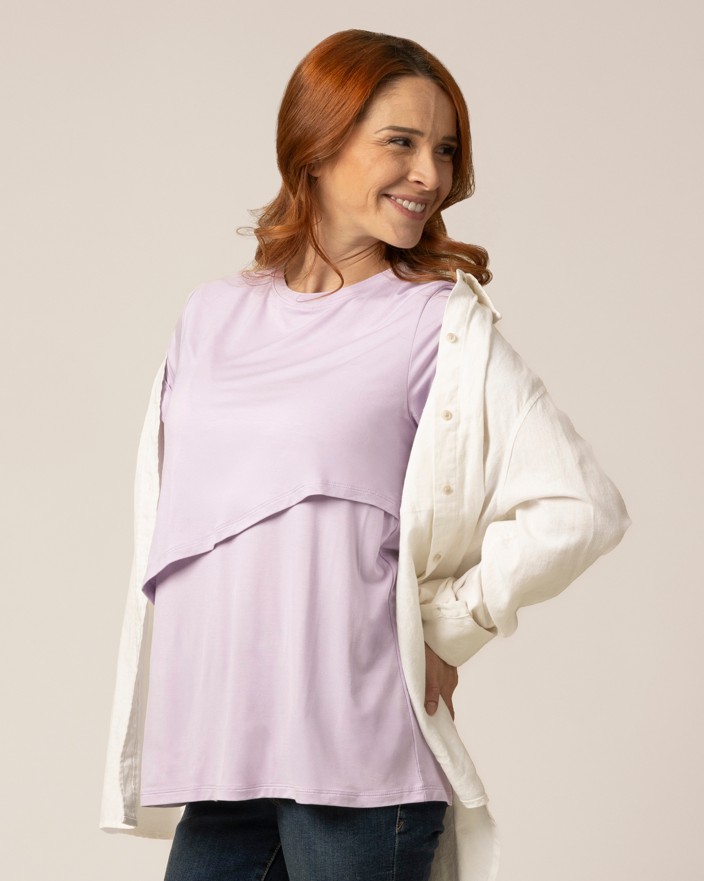 Model wearing the Everyday Asymmetrical Nursing T-shirt in Lavender Mist, paired with open button down