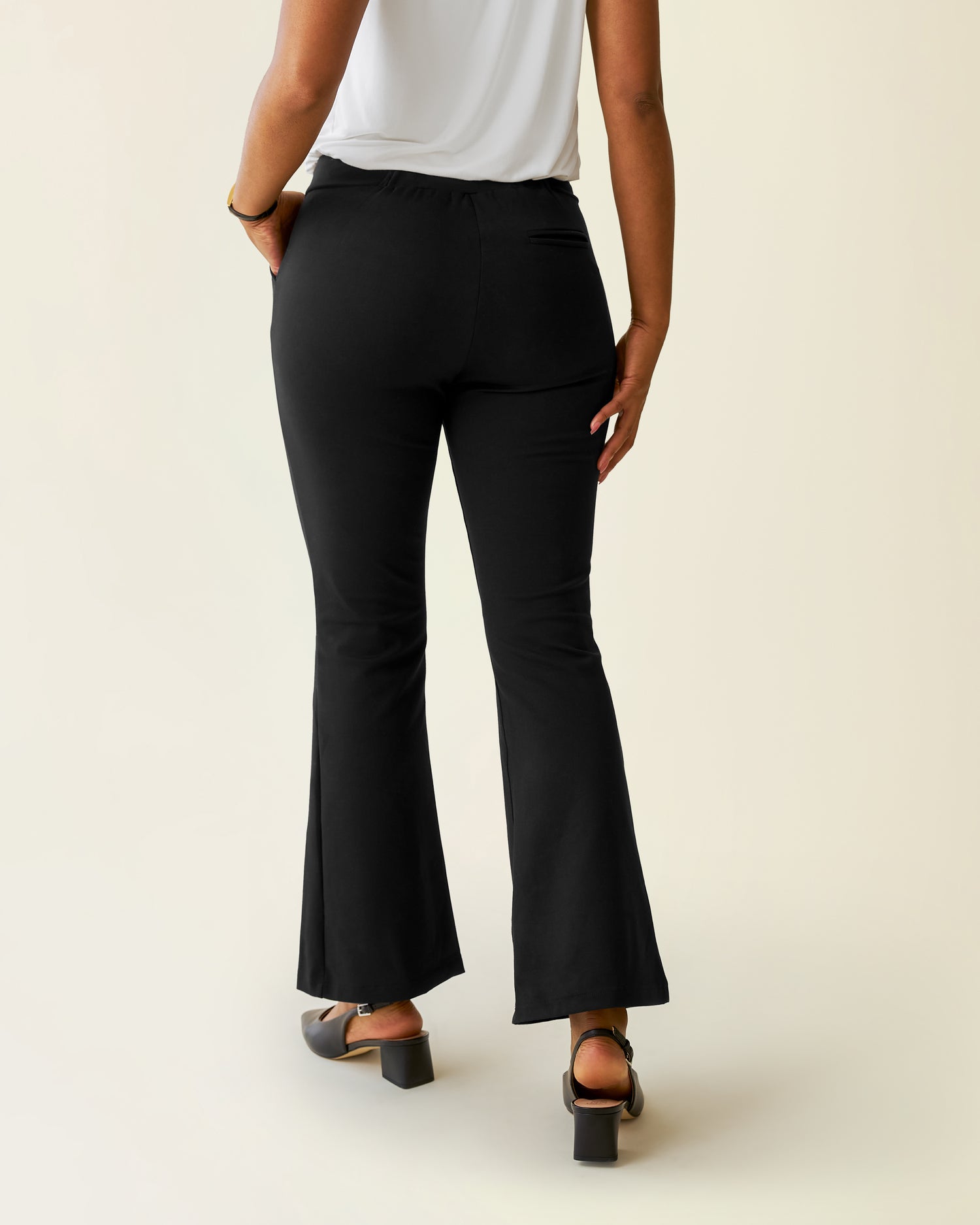 Woman wearing the Ponte Flare Pant with a white top, showing back of pants
