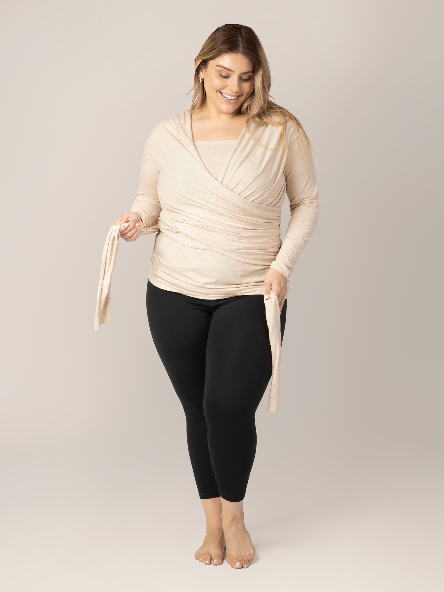 Model wearing the Organic Cotton Skin to Skin Long Sleeve Wrap Top in Oatmeal Heather, wrapping the straps around her torso