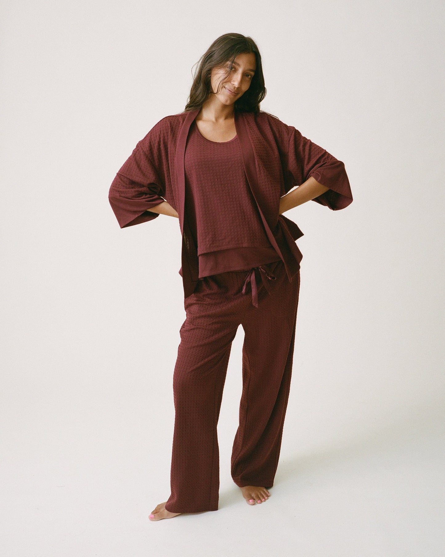 Model is wearing Waffle Maternity & Nursing Three-Piece Lounge Set in Garnet on a beige background.
