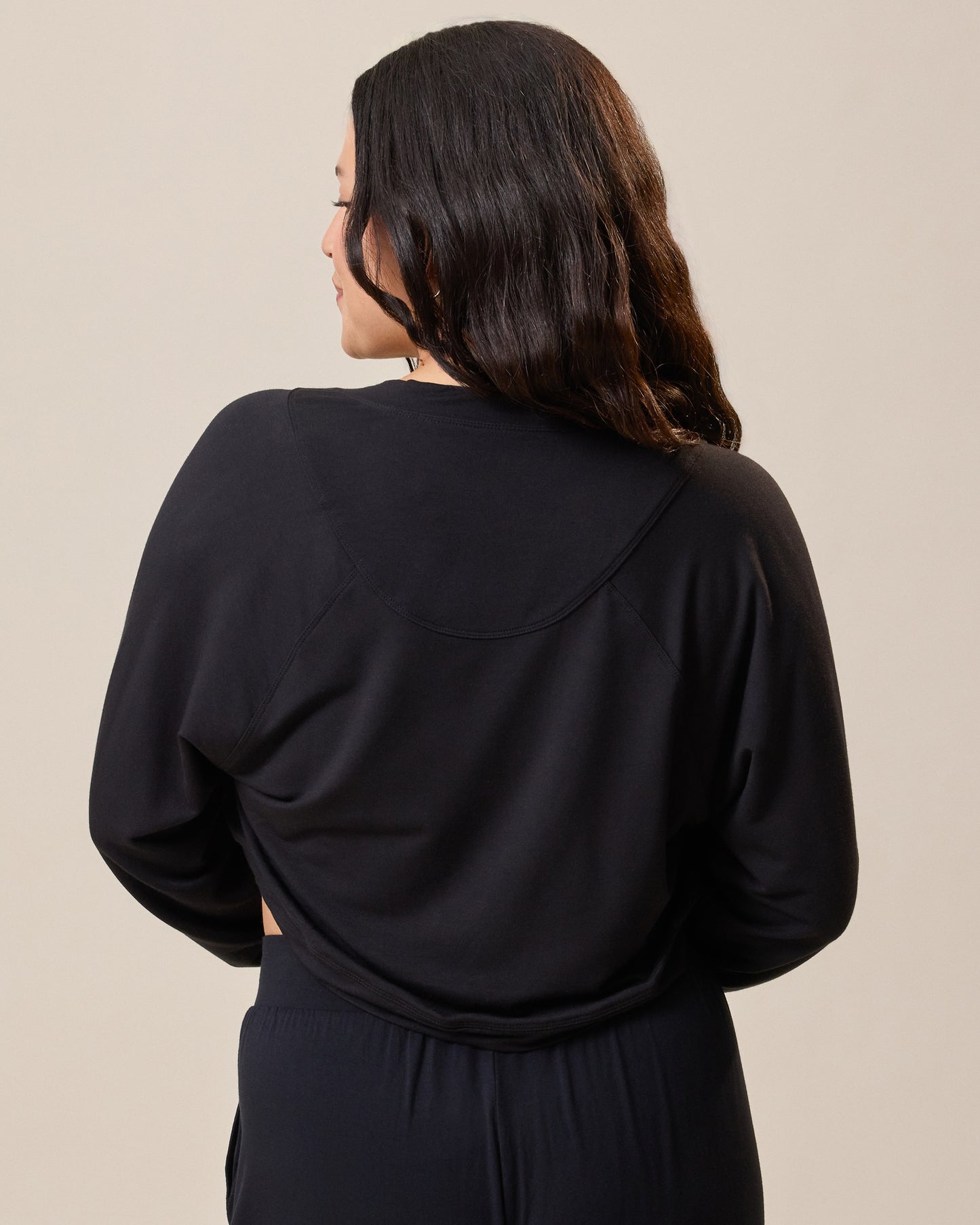 Back of the French Terry Cardigan Shrug in black on model against a beige background