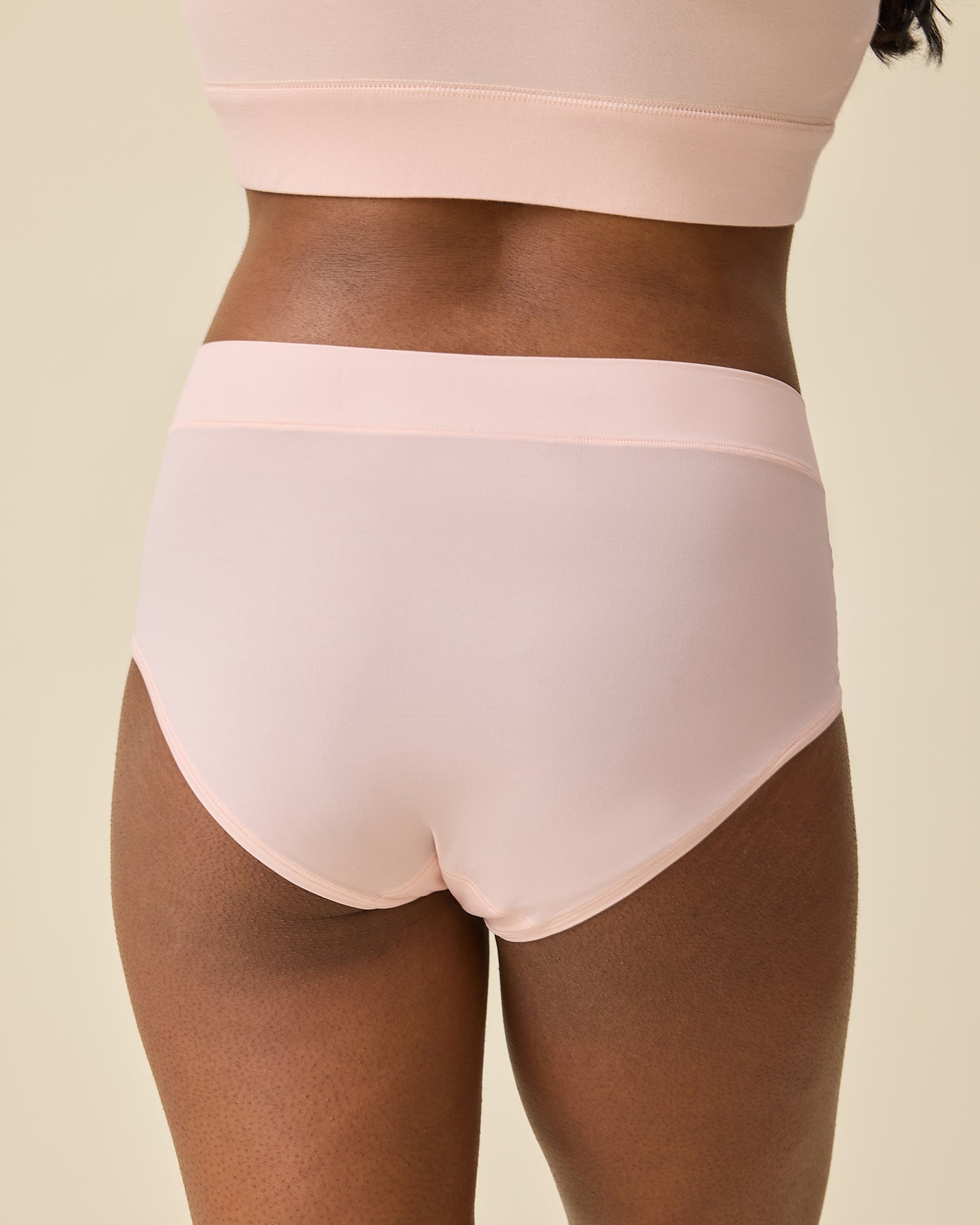Back view of model wearing Grow with Me™ Maternity & Postpartum Brief in Soft Pink on a beige background
