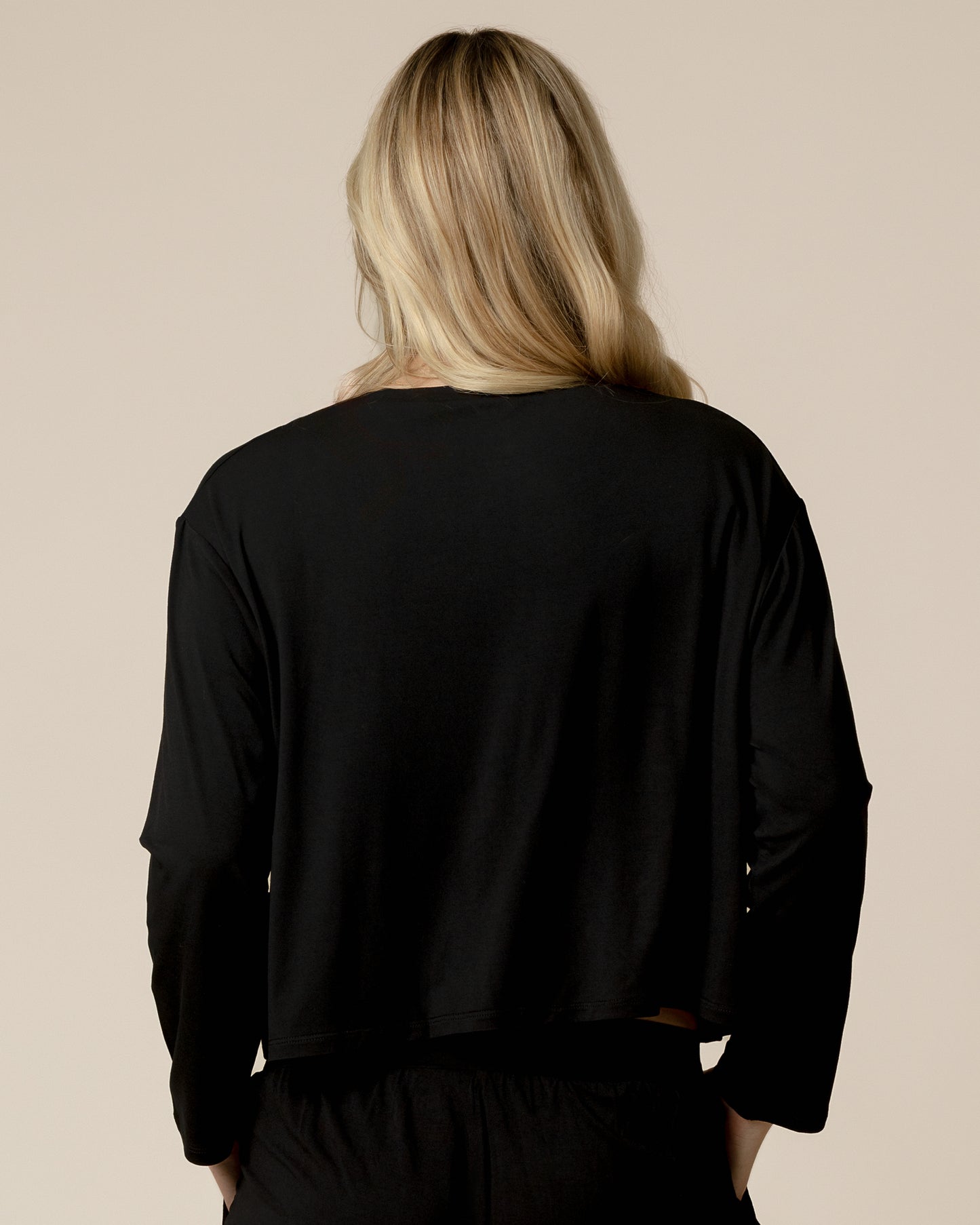 Back view of model wearing the Aria Bamboo Casual Cropped Long Sleeve Top in Black