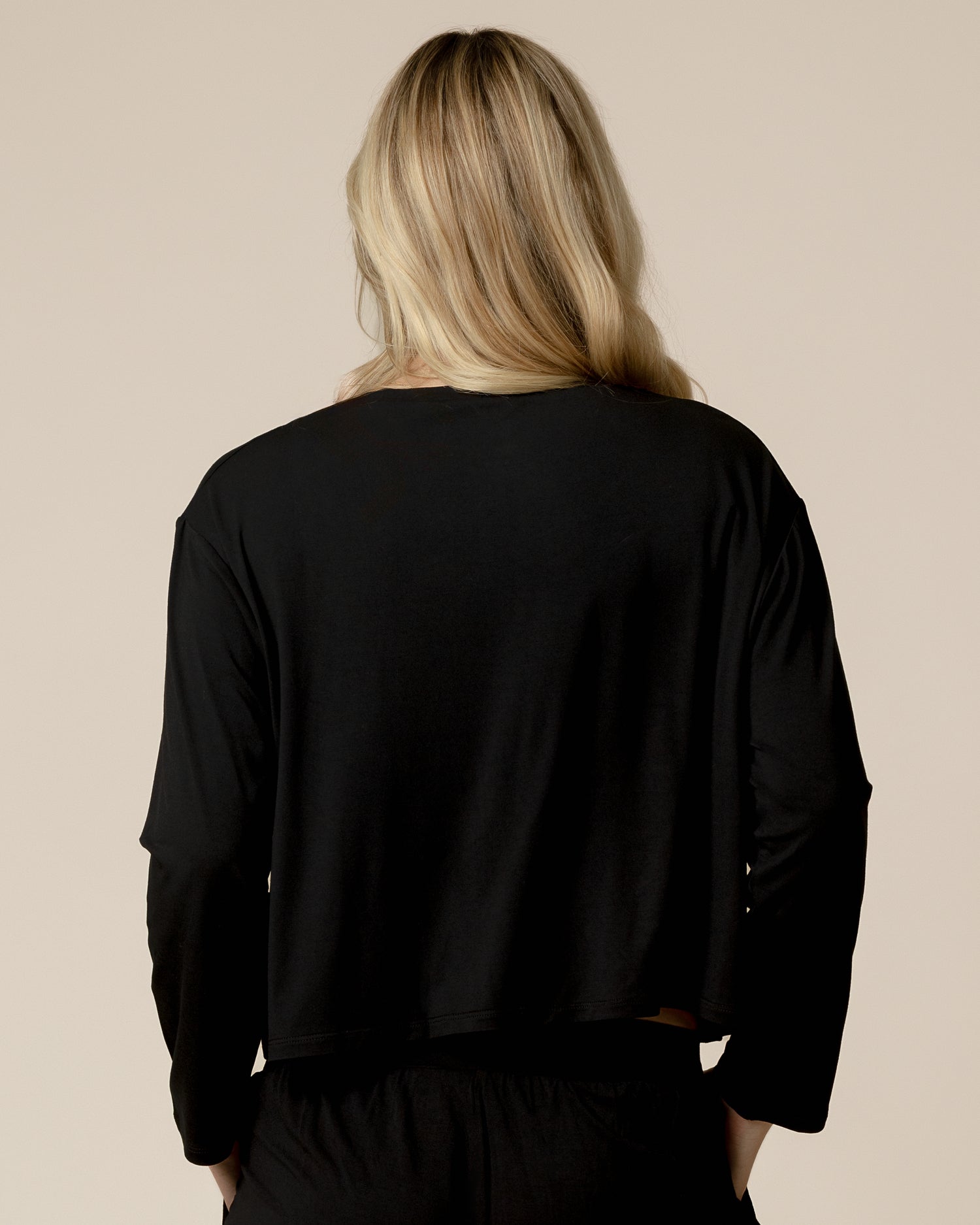 Back view of model wearing the Aria Bamboo Casual Cropped Long Sleeve Top in Black