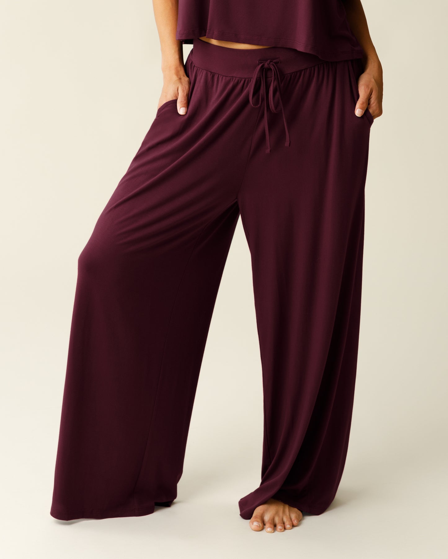 Woman wearing the Aria Bamboo Casual Lounge Pant in Deep Burgundy, with hands in pockets, showing wait down