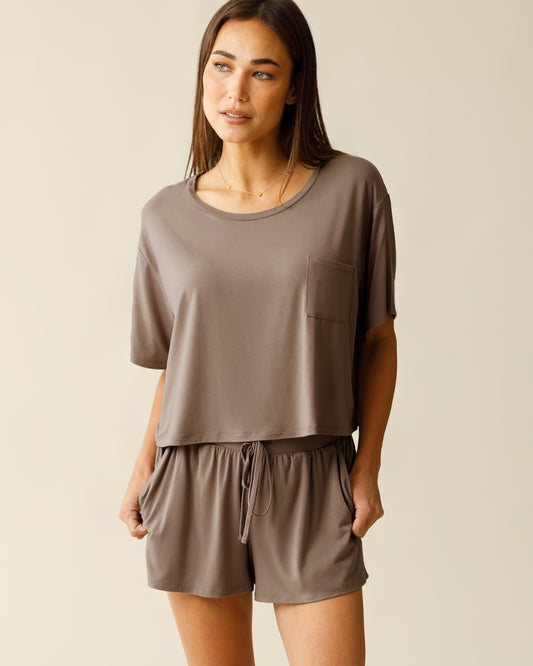 Woman wearing the Aria Bamboo Casual Cropped Short Sleeve Top in Taupe, paired with matching Aria Bamboo Casual Lounge Short, with hands in pockets@model_info:Lisa is 5'6" and wearing a Small.
