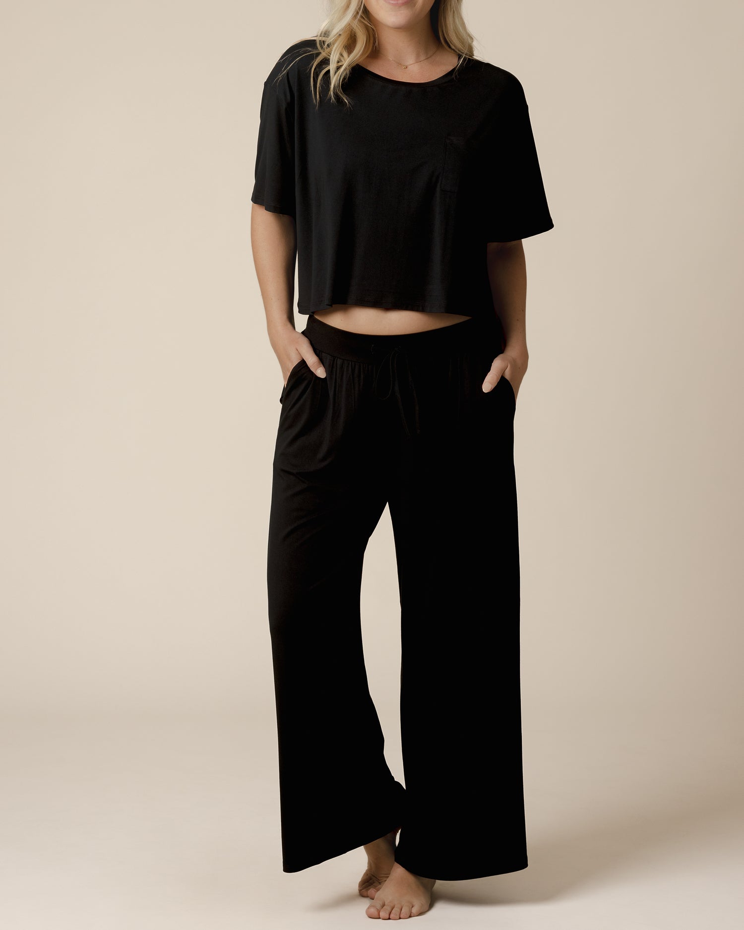 Front view of model wearing the Aria Bamboo Casual Lounge Pant in Black, with hands in pockets, and paired with matching Aria Bamboo Casual Cropped Short Sleeve Top @model_info:Maddy is 5'8" and wearing a Small