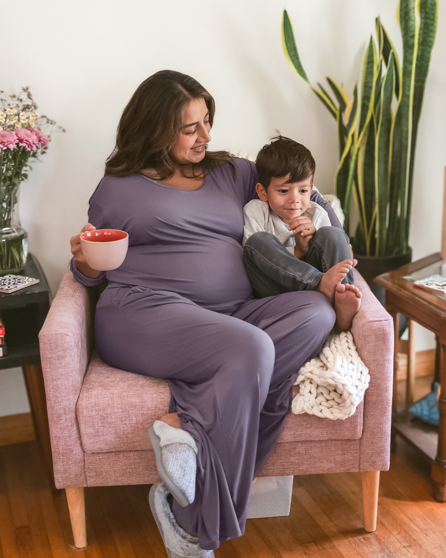 Pregnant model wearing the Aria Bamboo Casual Lounge Pant in Granite paired with matching Aria Bamboo Casual Cropped Long Sleeve Top, snuggled with toddler in chair