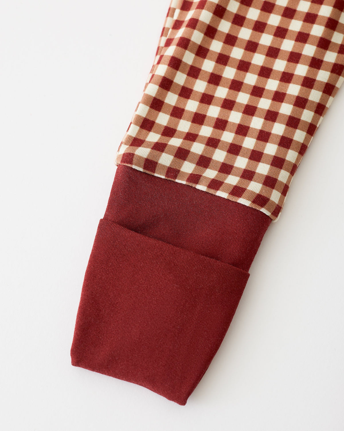 Close up of sleeve detail on Bamboo Baby Pajama in Auburn Gingham on an off white background.