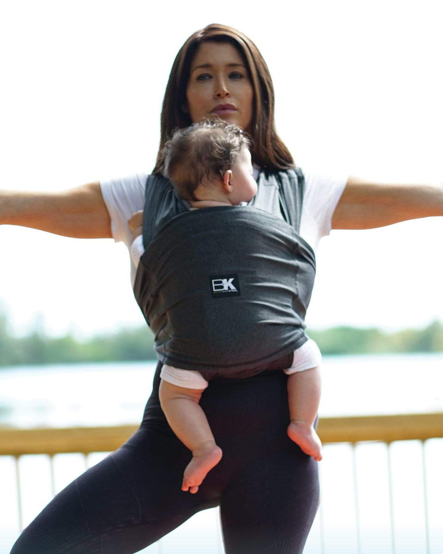 Model wearing baby in the Baby K'tan - Active Yoga Baby Carrier in Heather Black while doing a yoga pose