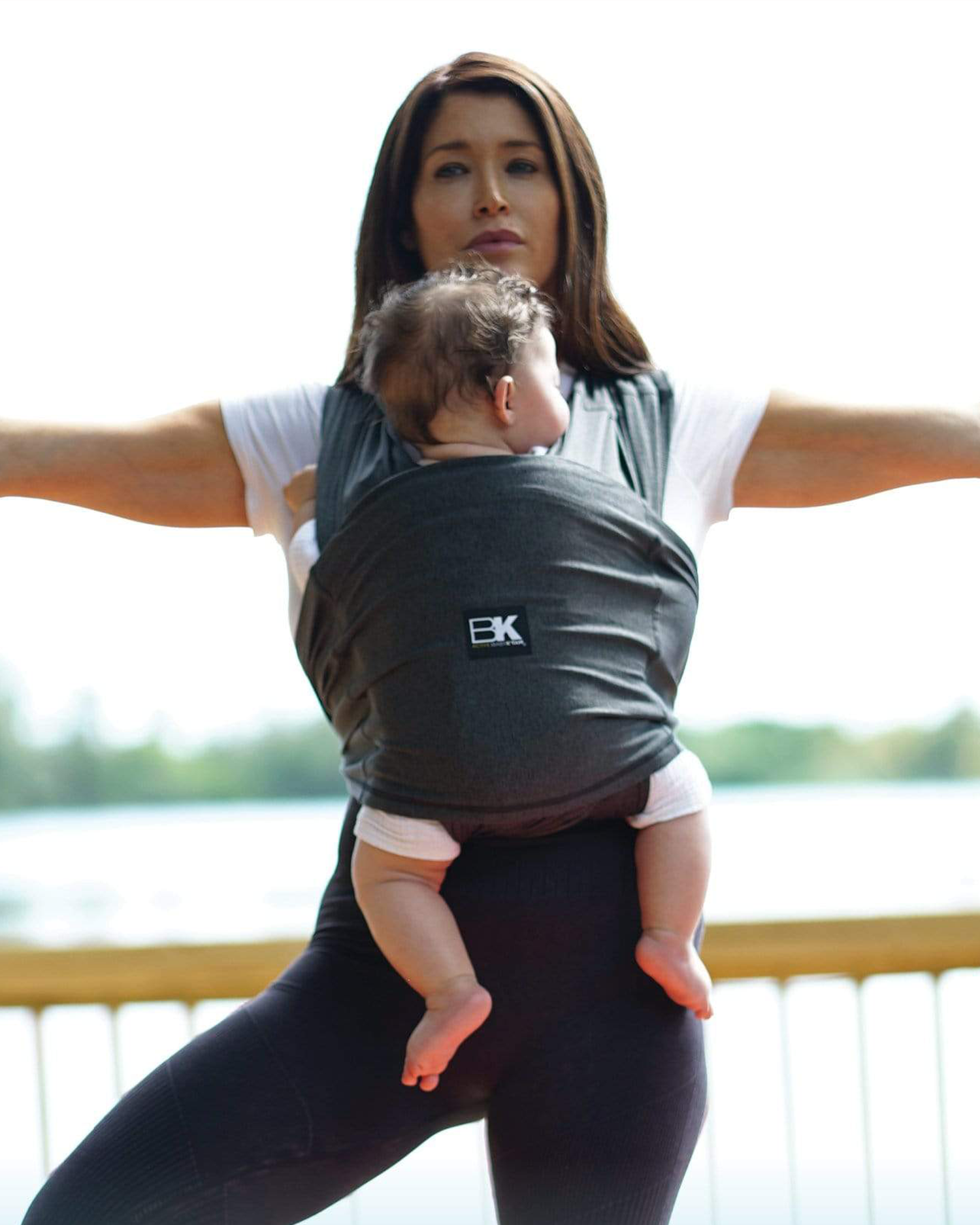 Model wearing baby in the Baby K'tan - Active Yoga Baby Carrier in Heather Black while doing a yoga pose