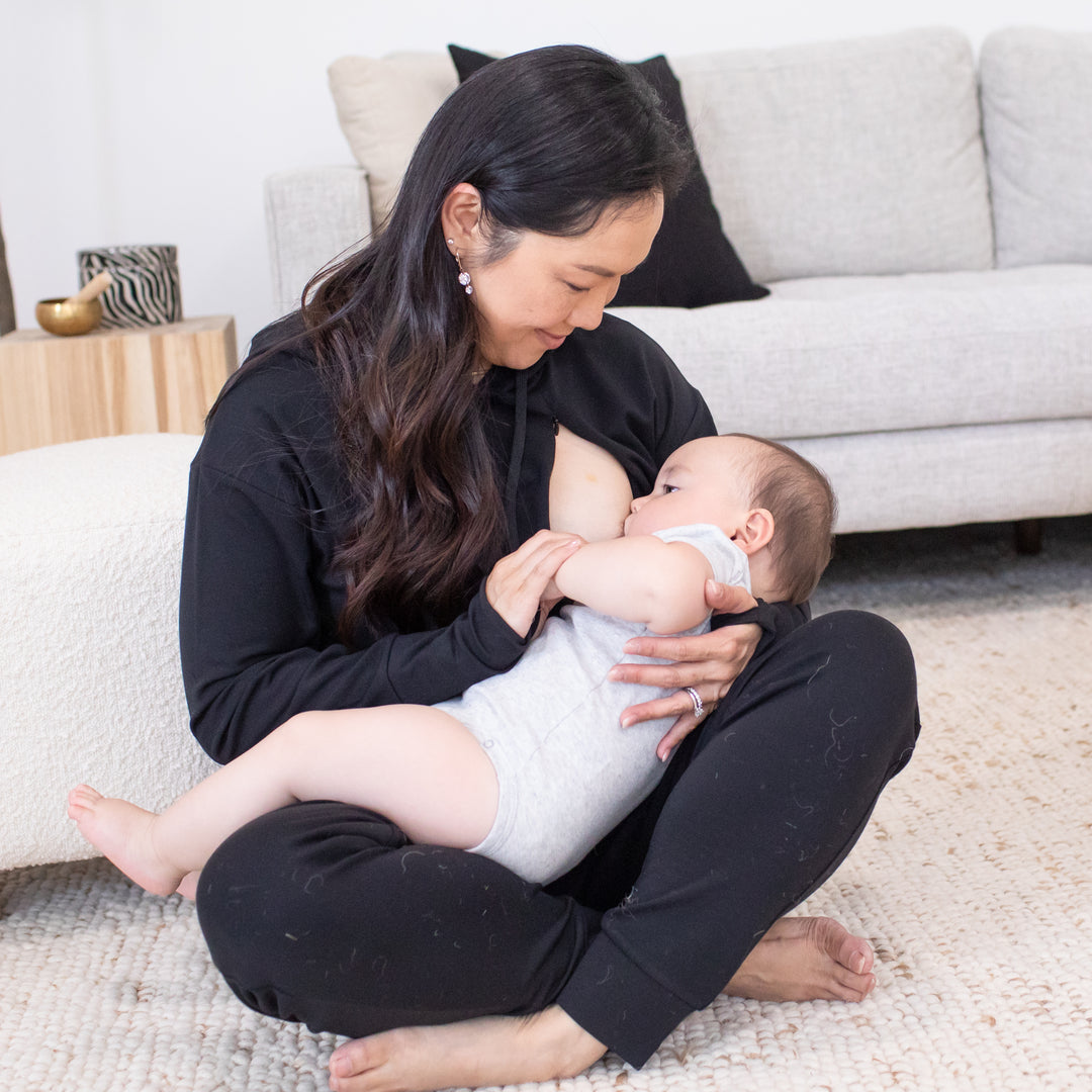 Model breastfeeding her baby while wearing the Bamboo Nursing Hoodie in Black