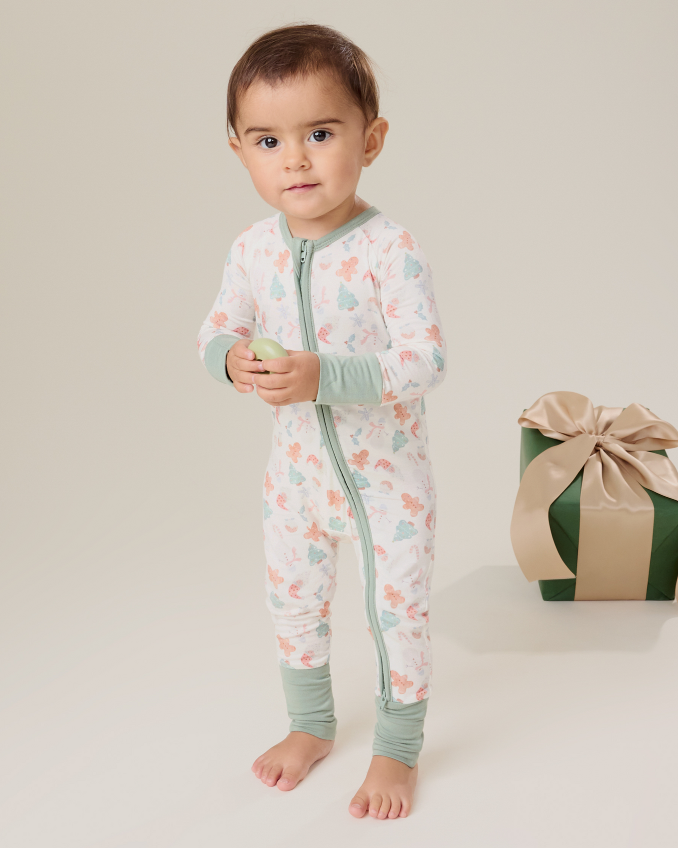 Baby wearing the Bamboo Baby Pajama in Cozy Holiday pattern with soft light green trim@model_info:Delilah is wearing 3-6 months.