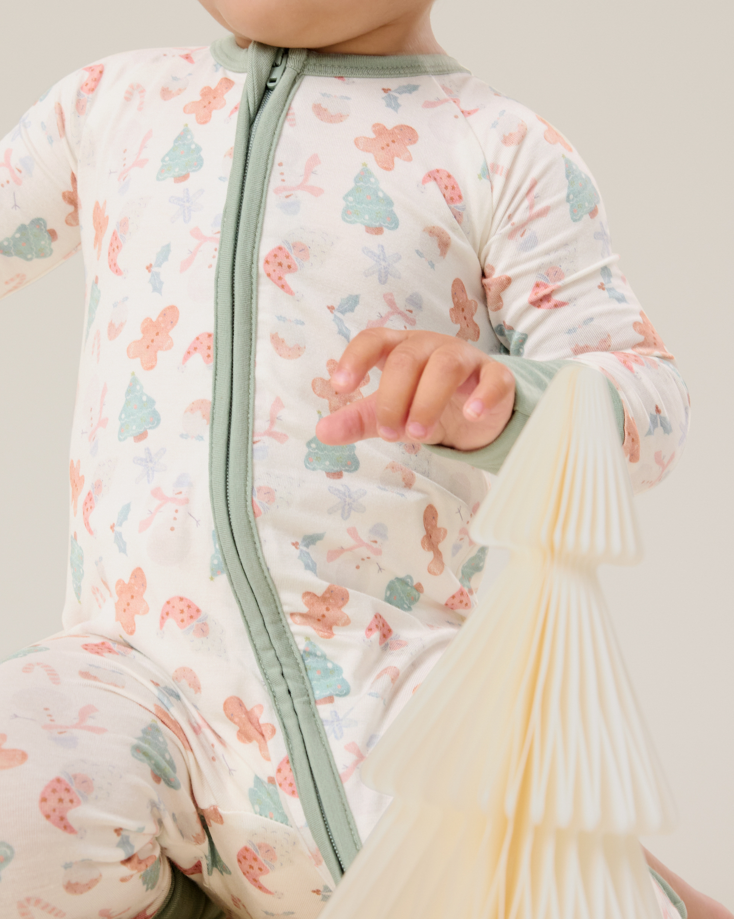 Baby wearing the Bamboo Baby Pajama in Cozy Holiday pattern with soft light green trim showing covered zipper detail