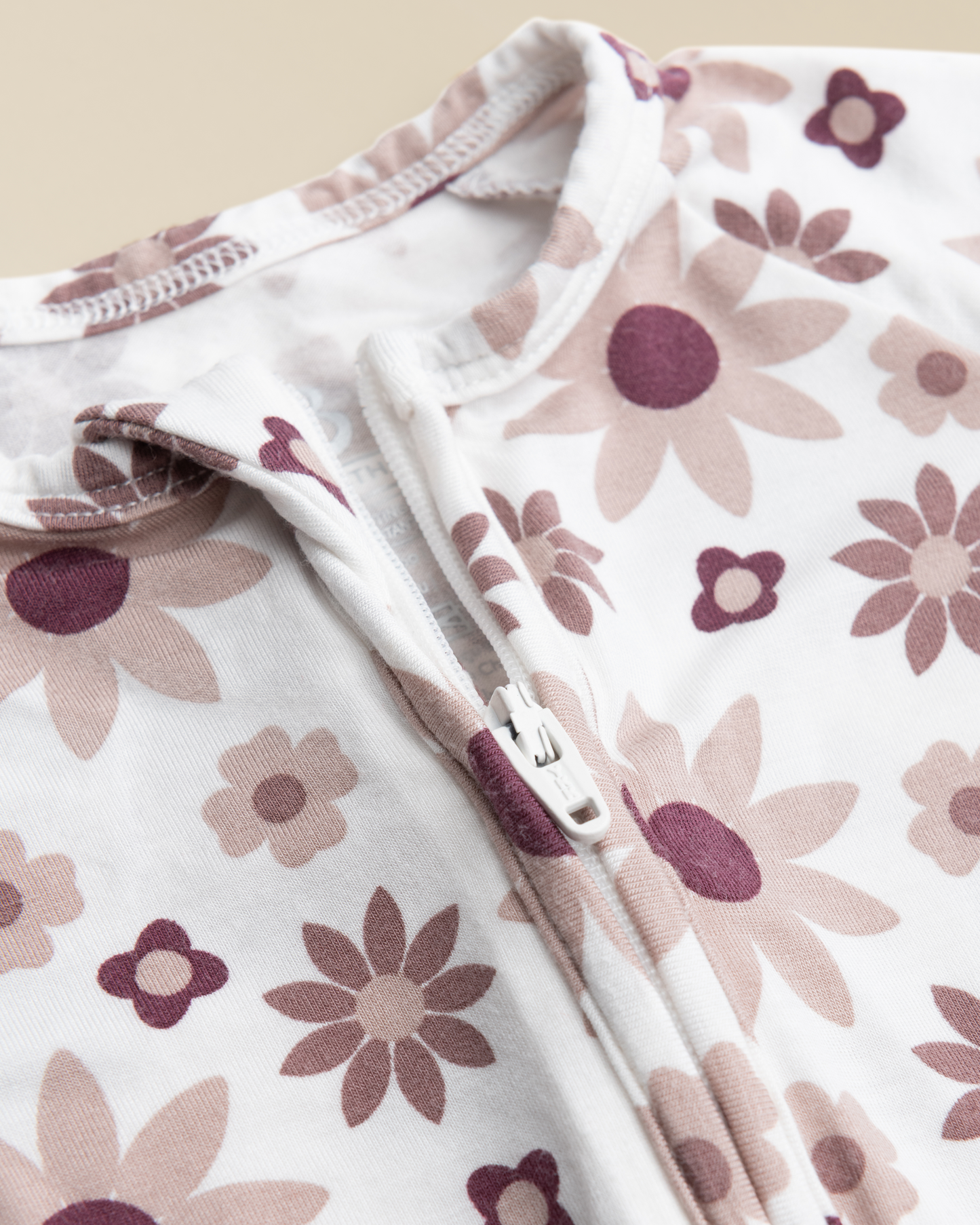 Close-up of Bamboo Baby Pajamas in Twilight Floral with a zipper on a beige background
