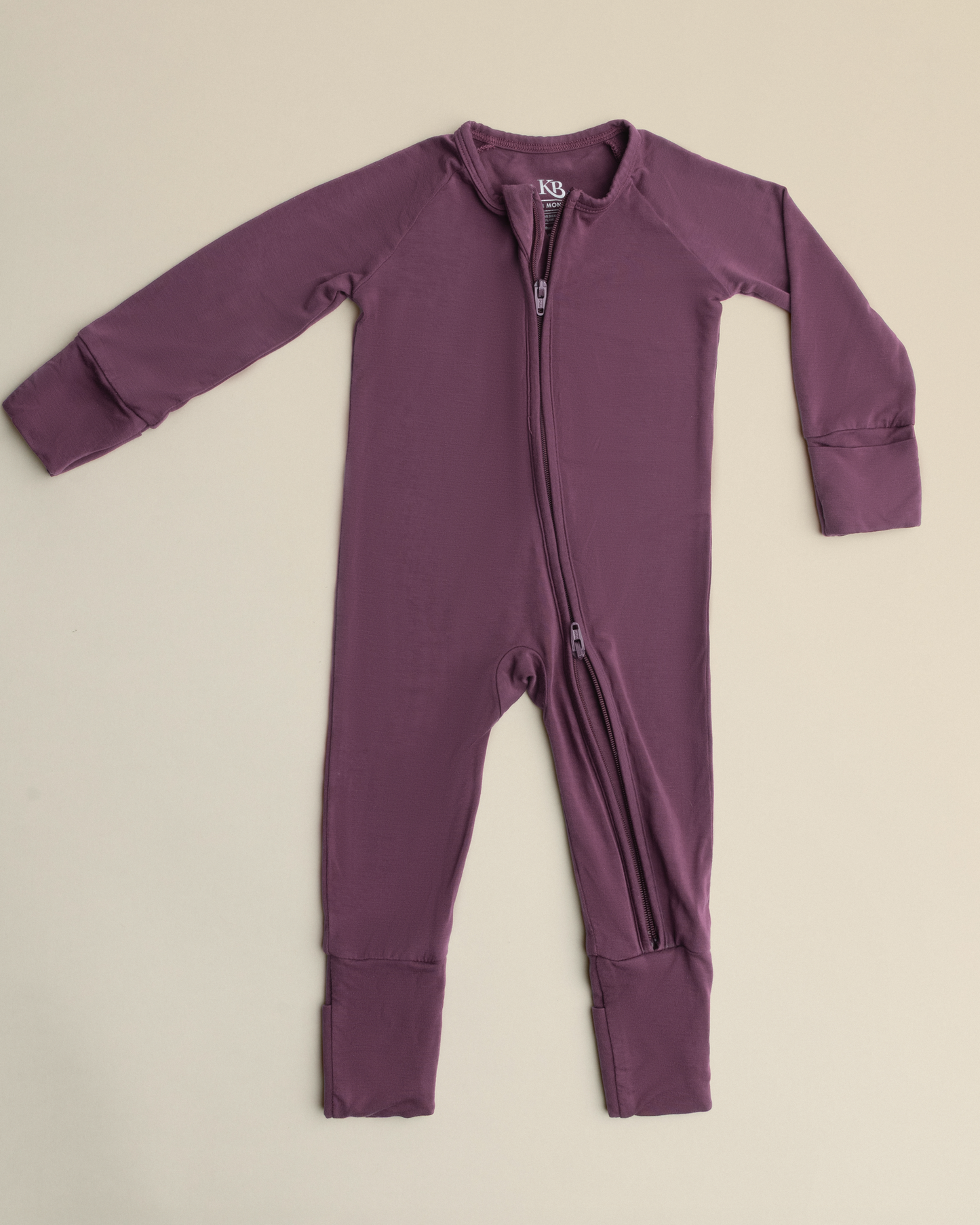 Bamboo Baby Pajamas in Burgundy Plum with a zipper on a beige background