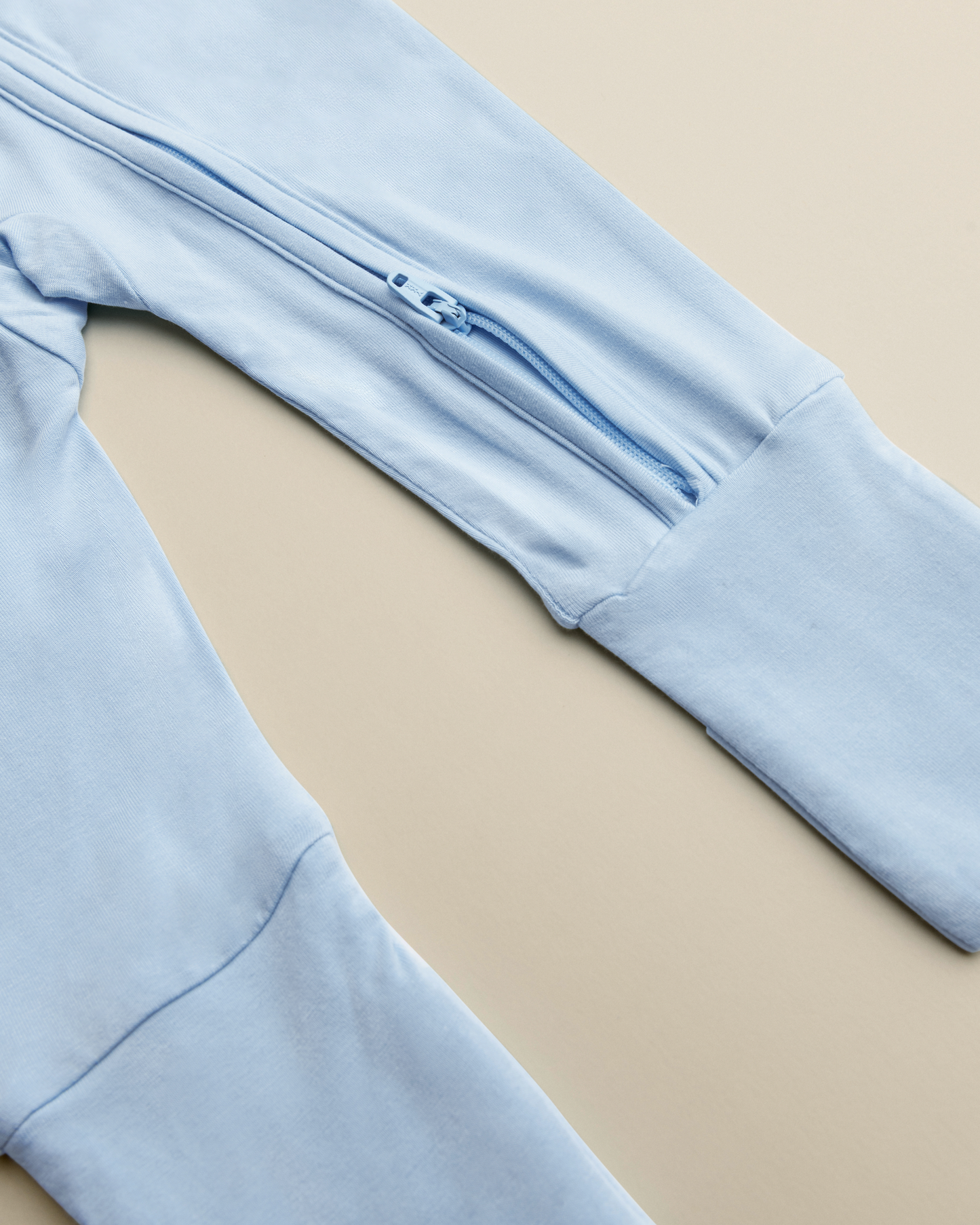 Close up of zipper on Bamboo Baby Pajamas in French Blue on a beige background