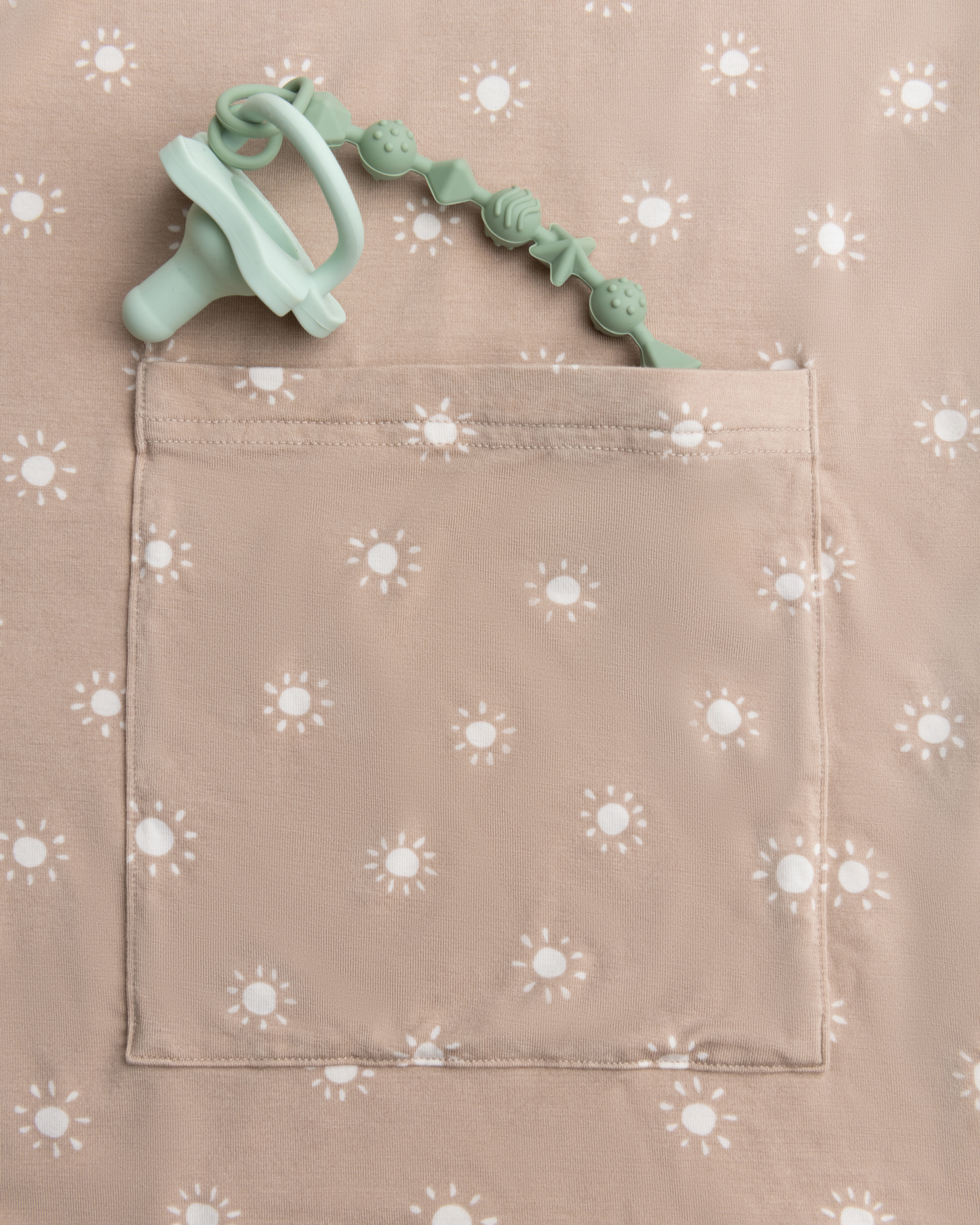 Pacifier sticking out the the pocket of Bamboo Multi-Use Nursing Cover in Fawn Sunburst