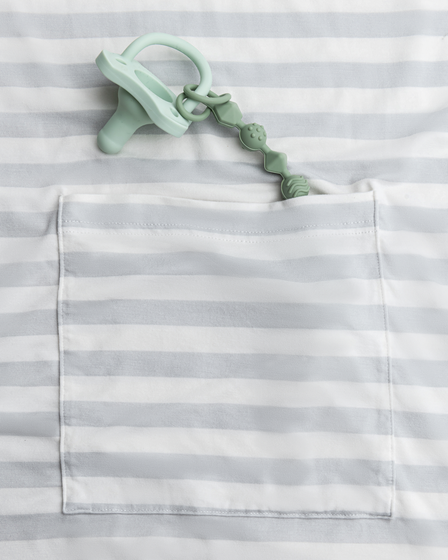 Mint green baby teether in the pocket of the Bamboo Multi-Use Nursing Cover in Grey Stripe