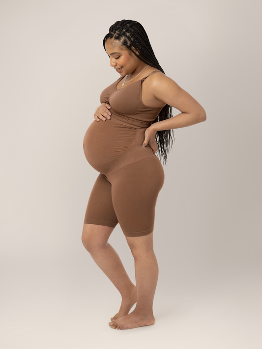 Model wearing the Seamless Bamboo Maternity Thigh Saver in Mocha with her hand on the small of her back. @model_info:Ruby is wearing a Medium.