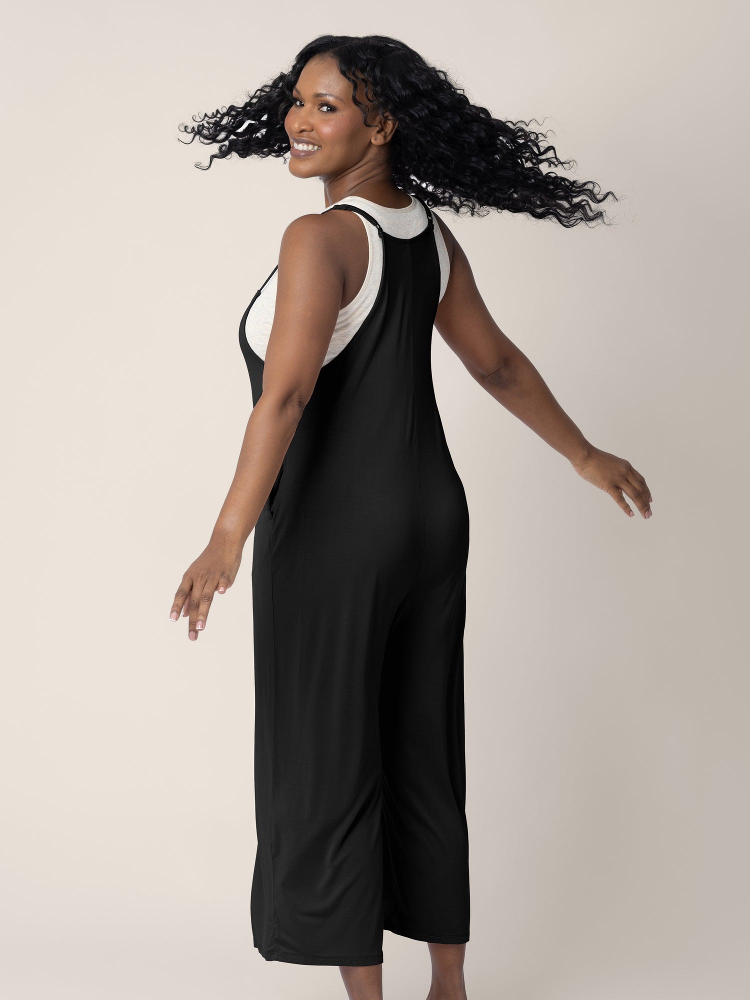 A model wearing the Charlie Maternity & Nursing Romper in Black, giving a spin