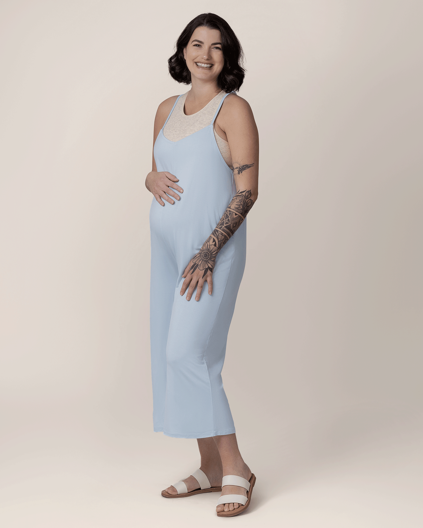 Pregnant model with hand on belly wearing the Charlie Maternity & Nursing Romper in French Blue, paired with Sublime® Bamboo Maternity & Nursing Longline Bra Top in Oatmeal Heather and flat sandals. @model_info:Emily is 5'8" and wearing a Medium.